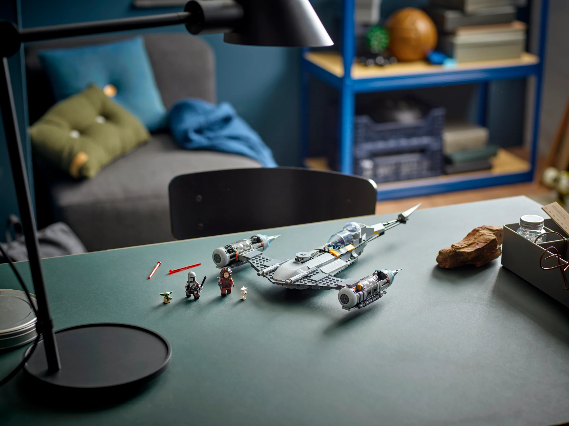 Imagine cu Starfighterul N-1 Mandalorian, cu minifigurinele asociate, pe o masă verde.