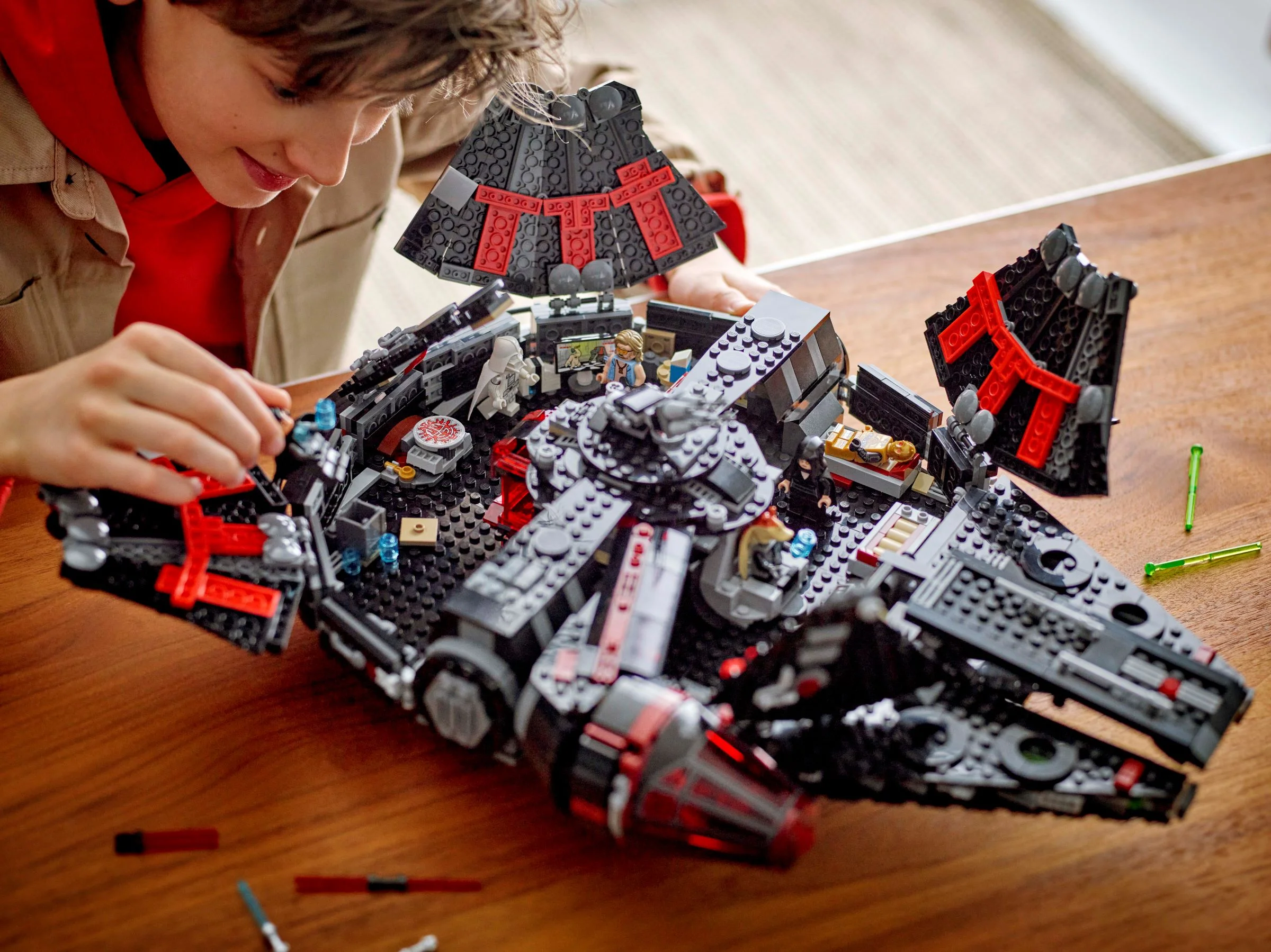 Copil construind Millennium Falcon întunecat LEGO Star Wars, cu detalii interioare vizibile.
