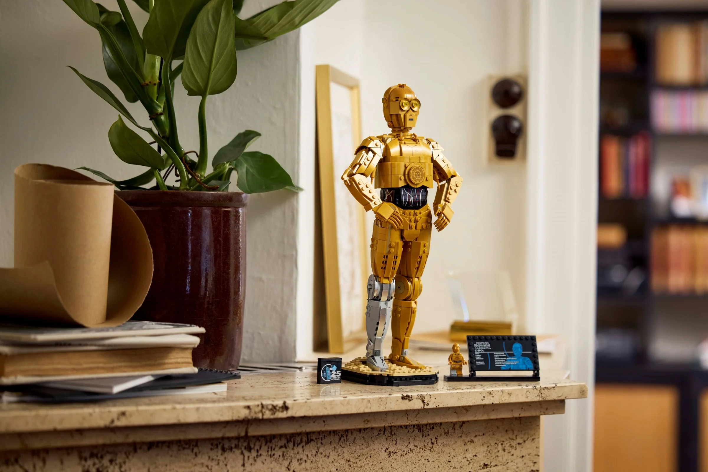 C-3PO LEGO, o statuetă detaliată, cu minifigurina și plăcuța informativă, într-un cadru de interior.