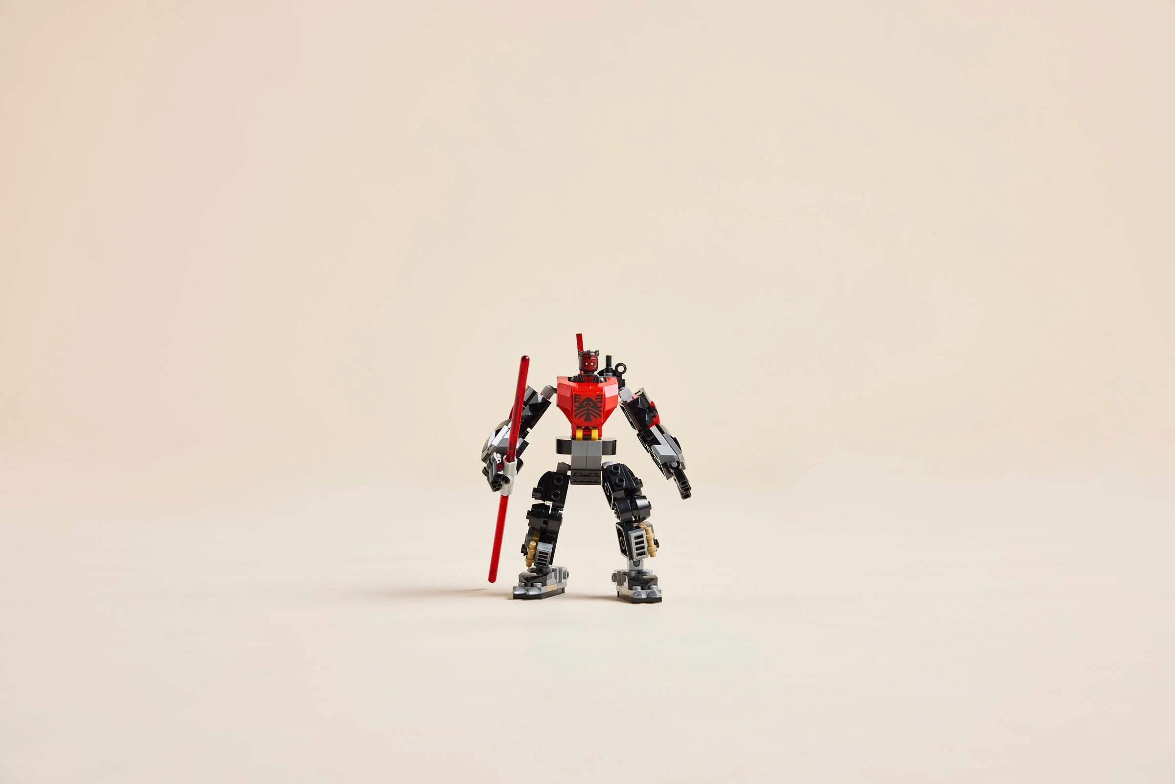 Darth Maul Mech LEGO stă impunător, cu sabie laser roșie. Design detaliat, roșu și negru.