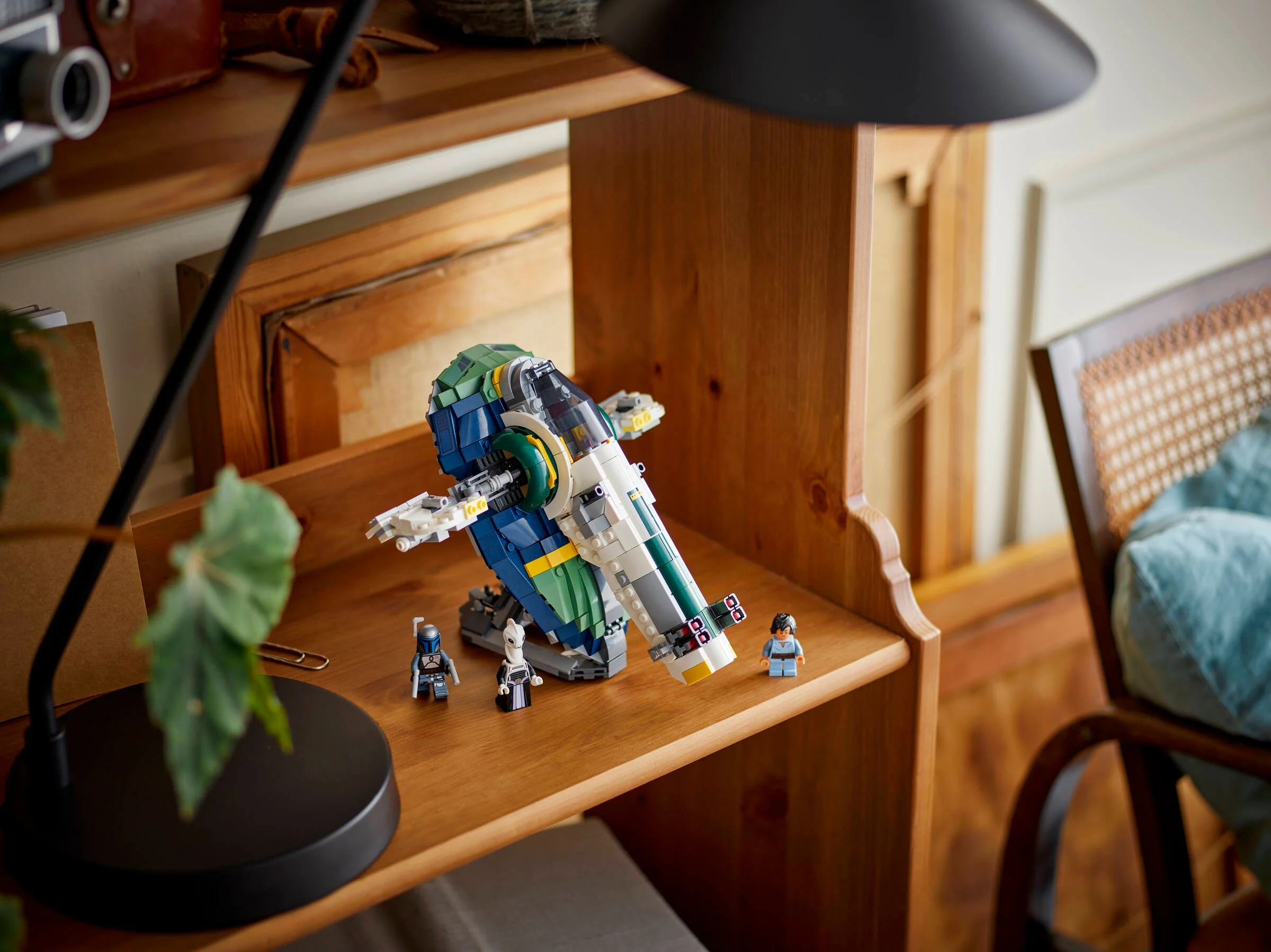 Modelul Jango Fett's Starship (75343) LEGO Star Wars pe un raft, cu minifigurine.