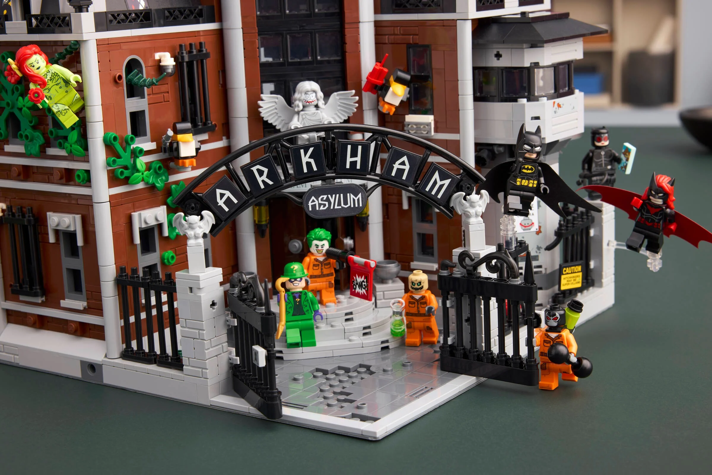 O imagine cu setul LEGO 76300 Arkham Asylum, ce include minifigurine și detalii ale clădirii.