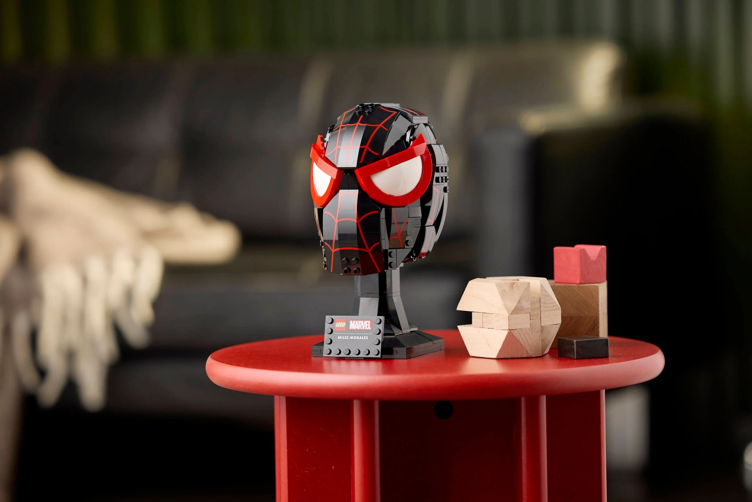 Imagine cu masca LEGO Miles Morales pe o măsuță roșie, într-un cadru modern.