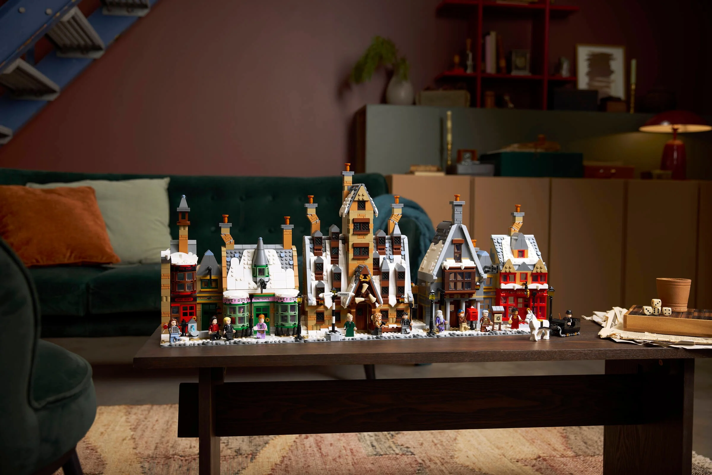 Imagine cu setul LEGO Hogsmeade, ediție de colecție, pe o măsuță. Detalii arhitecturale, minifigurine și zăpadă.