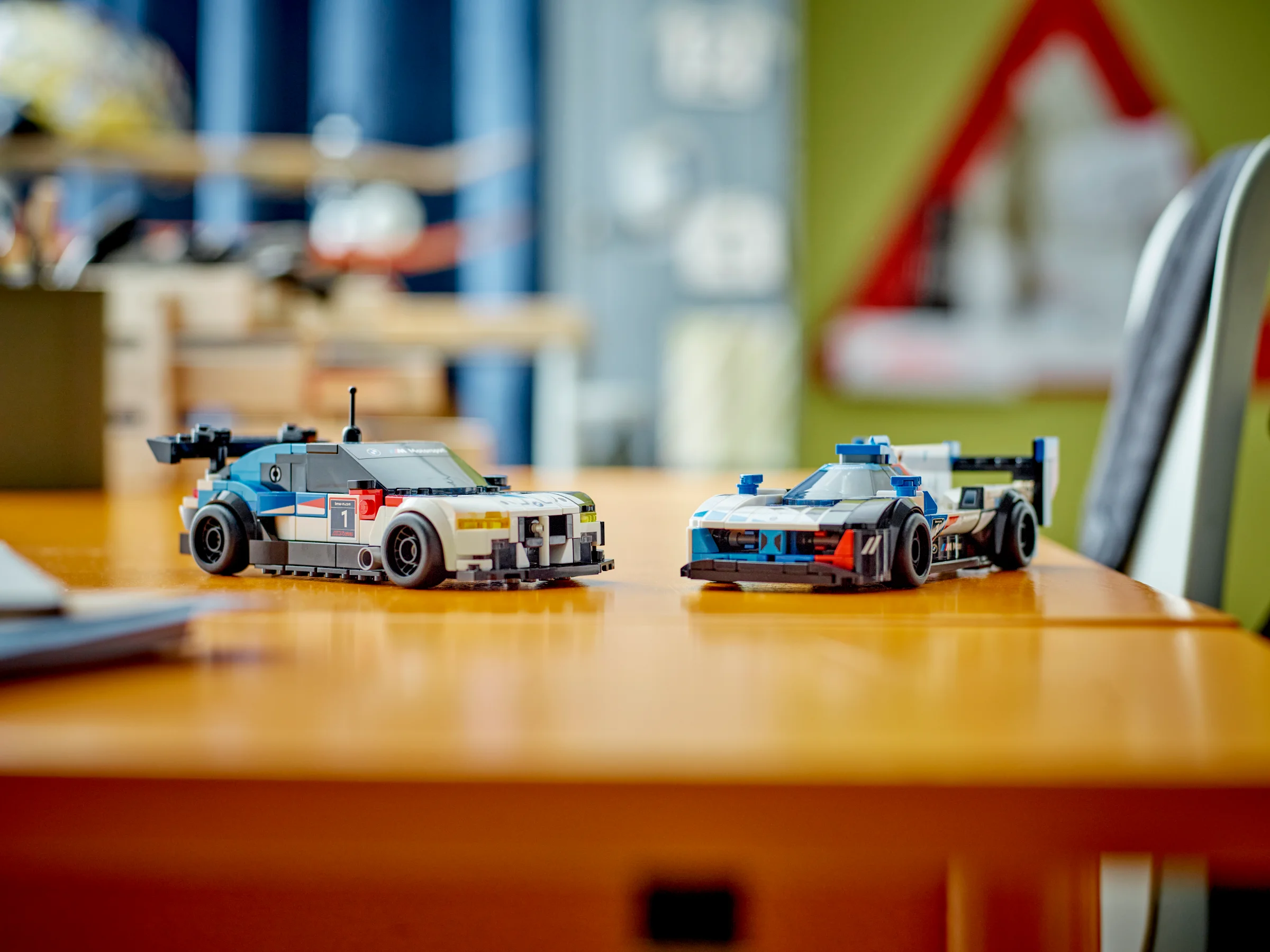 Două mașini BMW, M4 GT3 și M Hybrid V8, prezentate pe o masă. Design detaliat.