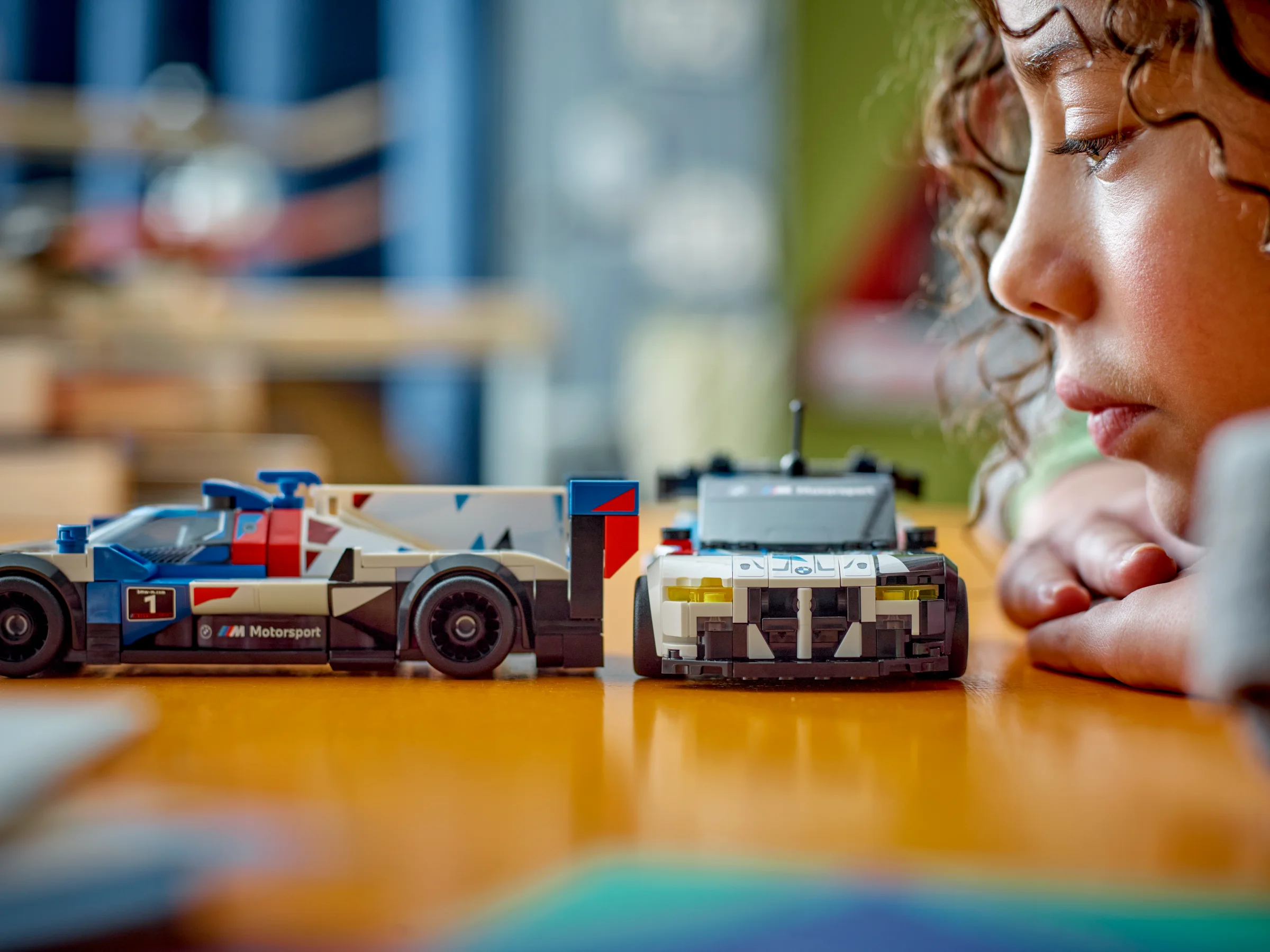 Prim plan cu modelele LEGO BMW și un copil concentrat, posibil construindu-le. 