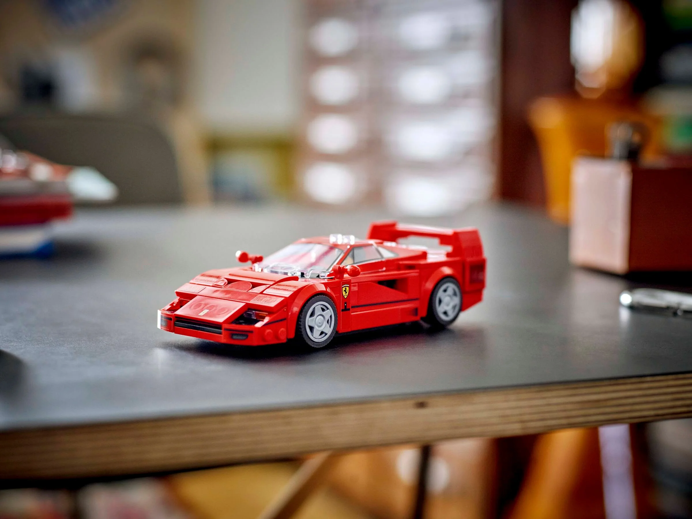 Modelul LEGO Ferrari F40 roșu, expus pe o suprafață gri. Detalii precise și un design atractiv.
