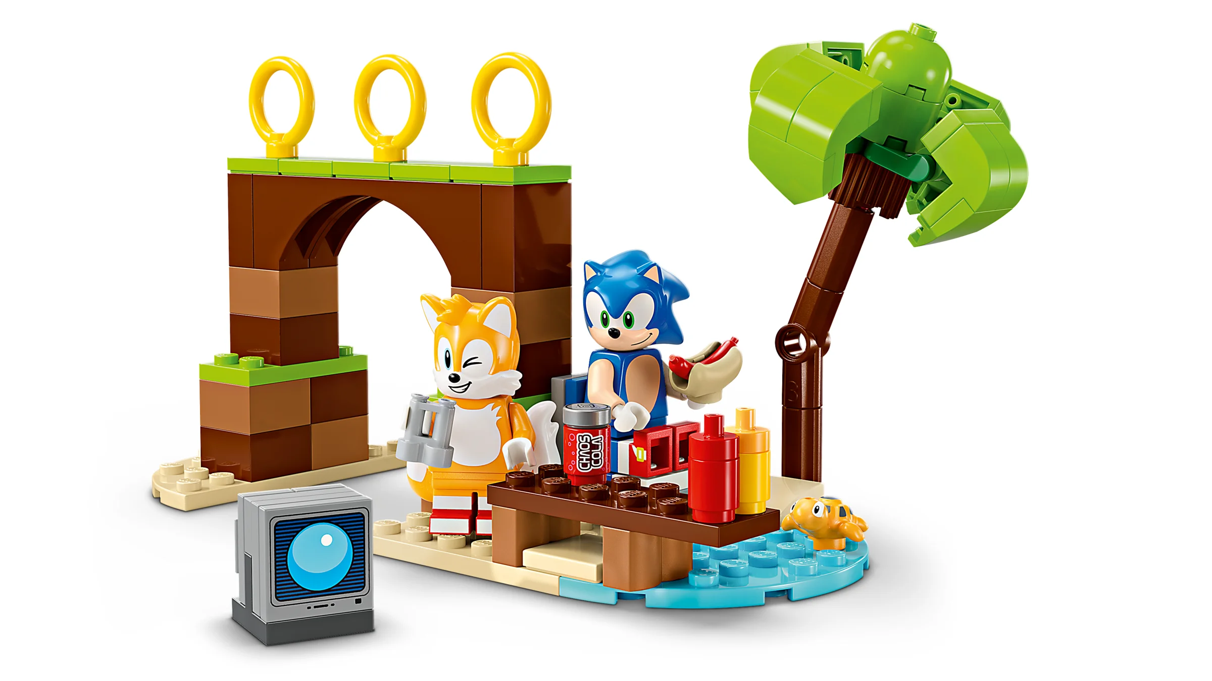 Setul LEGO 76997 cu Tails și Sonic la picnic, lângă un palmier și inelele caracteristice.