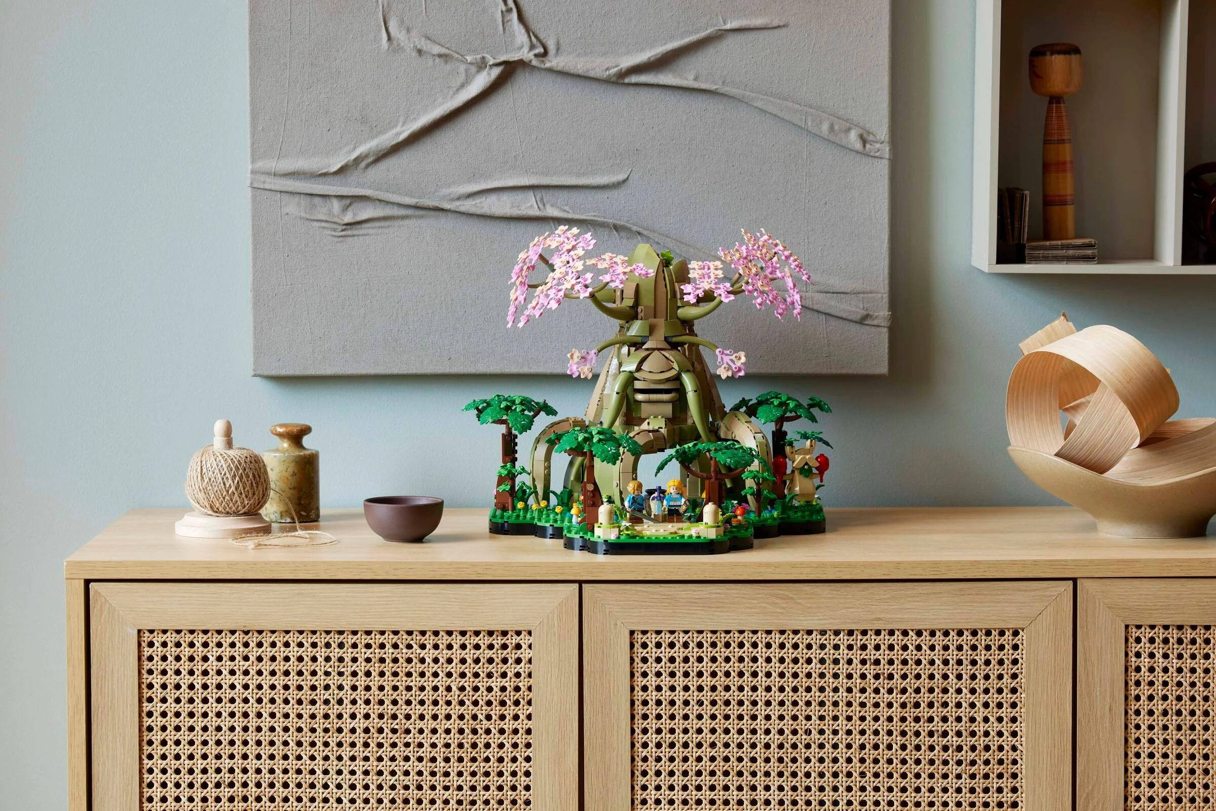 Lego 77092 Arborele Deku, expus elegant pe o mobilă. Florile roz încântă privirea.