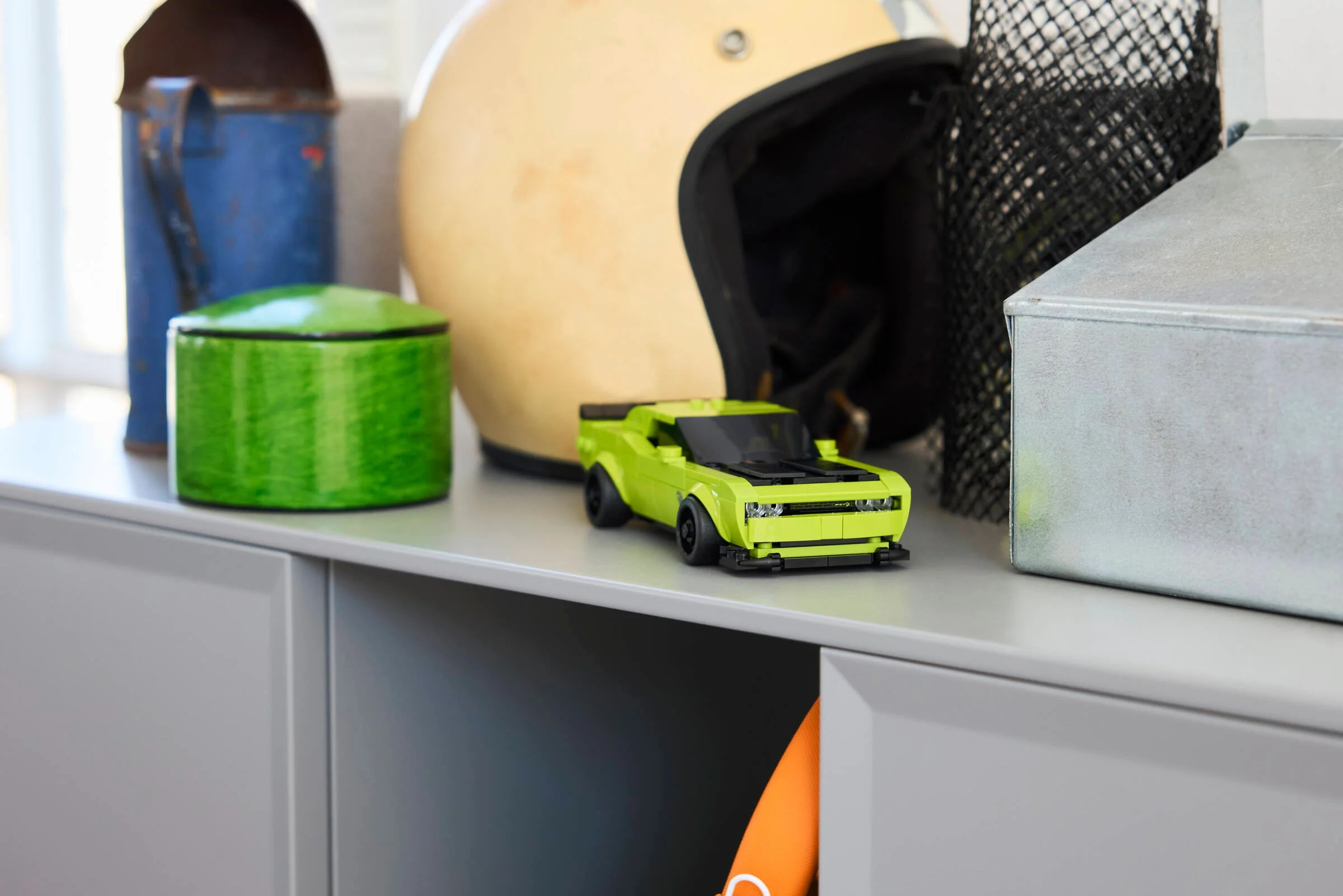 Modelul Dodge Challenger SRT Hellcat, verde lime, expus pe un raft, lângă diverse obiecte decorative.