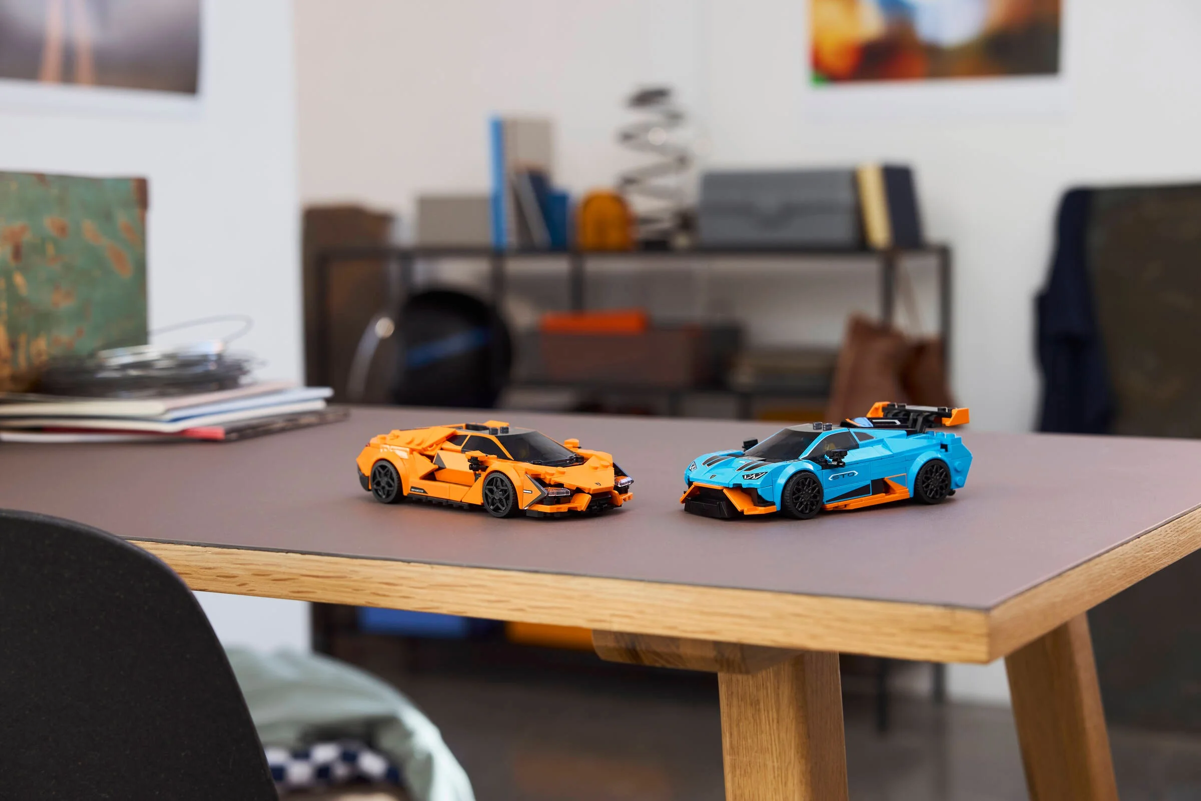 Imagine cu cele două modele Lamborghini, portocaliu și albastru, pe o masă. Detalii interesante.