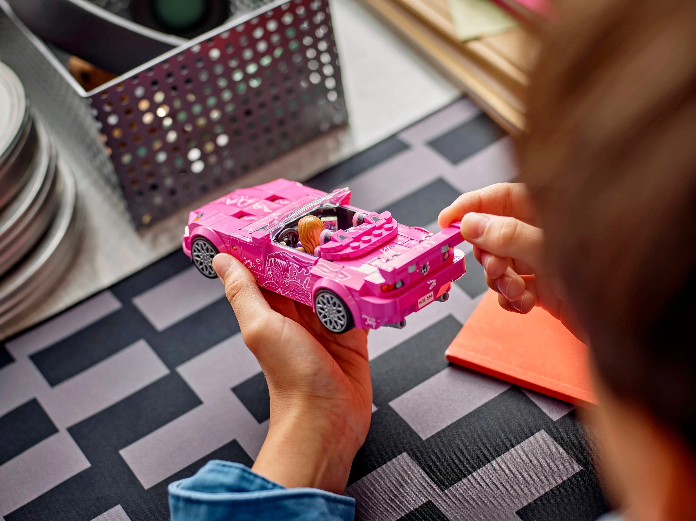 Mașină LEGO Honda S2000 roz, ținută în mână, cu detalii și minifigurină vizibile.