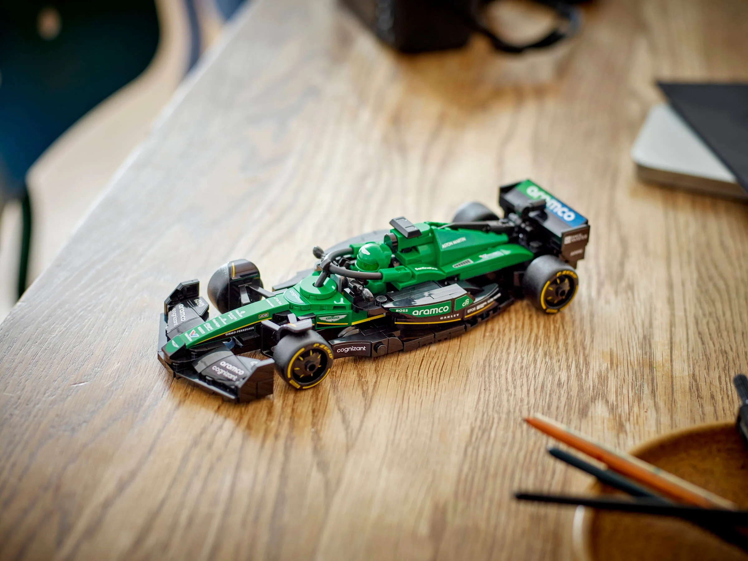 Mașină Aston Martin F1 AMR24 LEGO, verde și neagră, pe o masă de lemn. Detaliu.
