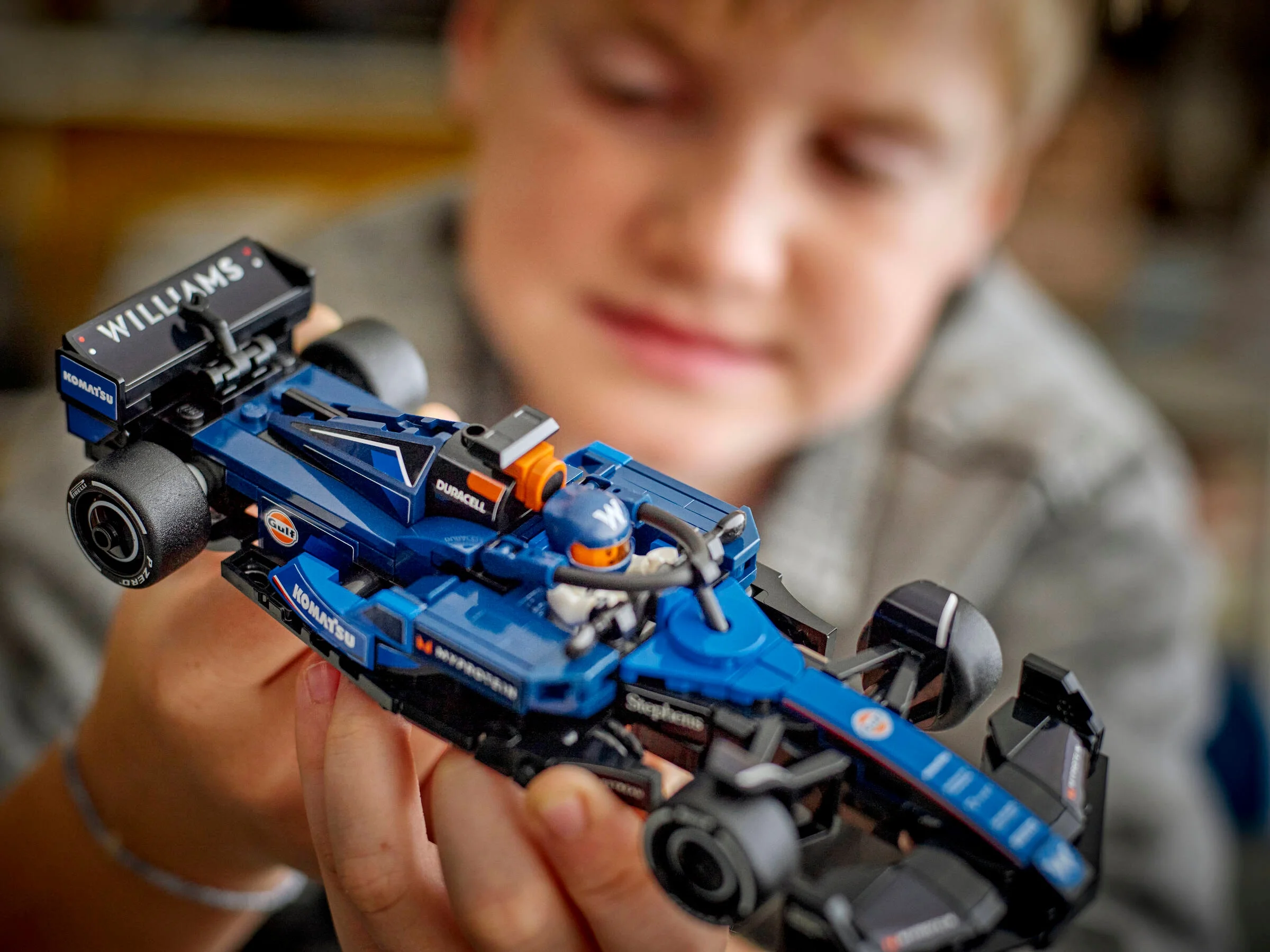 Prim-plan cu modelul LEGO Williams Racing FW46 ținut de o persoană. Model detaliat, albastru și negru.