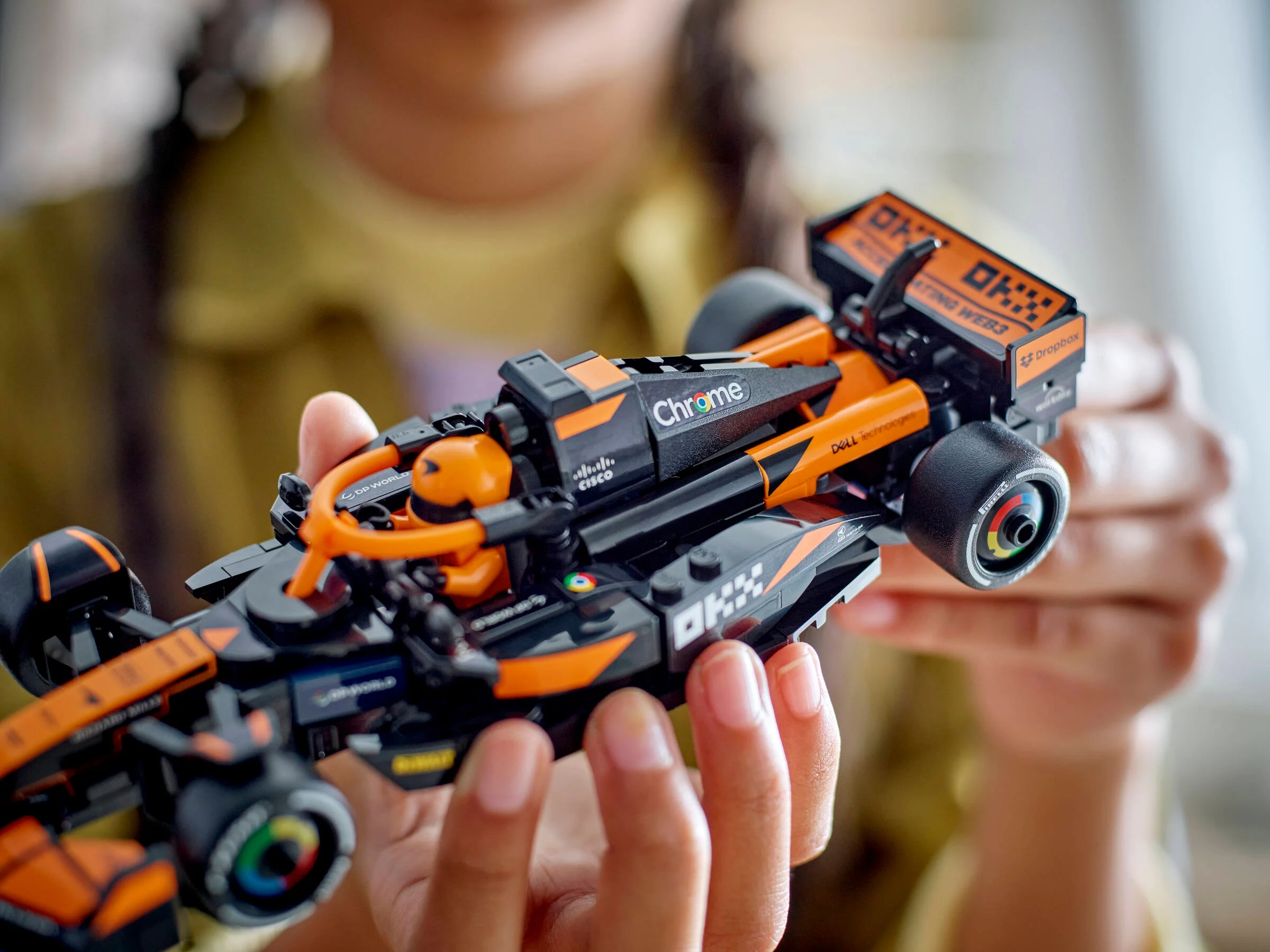 Prim-plan cu modelul LEGO McLaren F1 Team MCL38, ținut în mână. Detalii atractive.