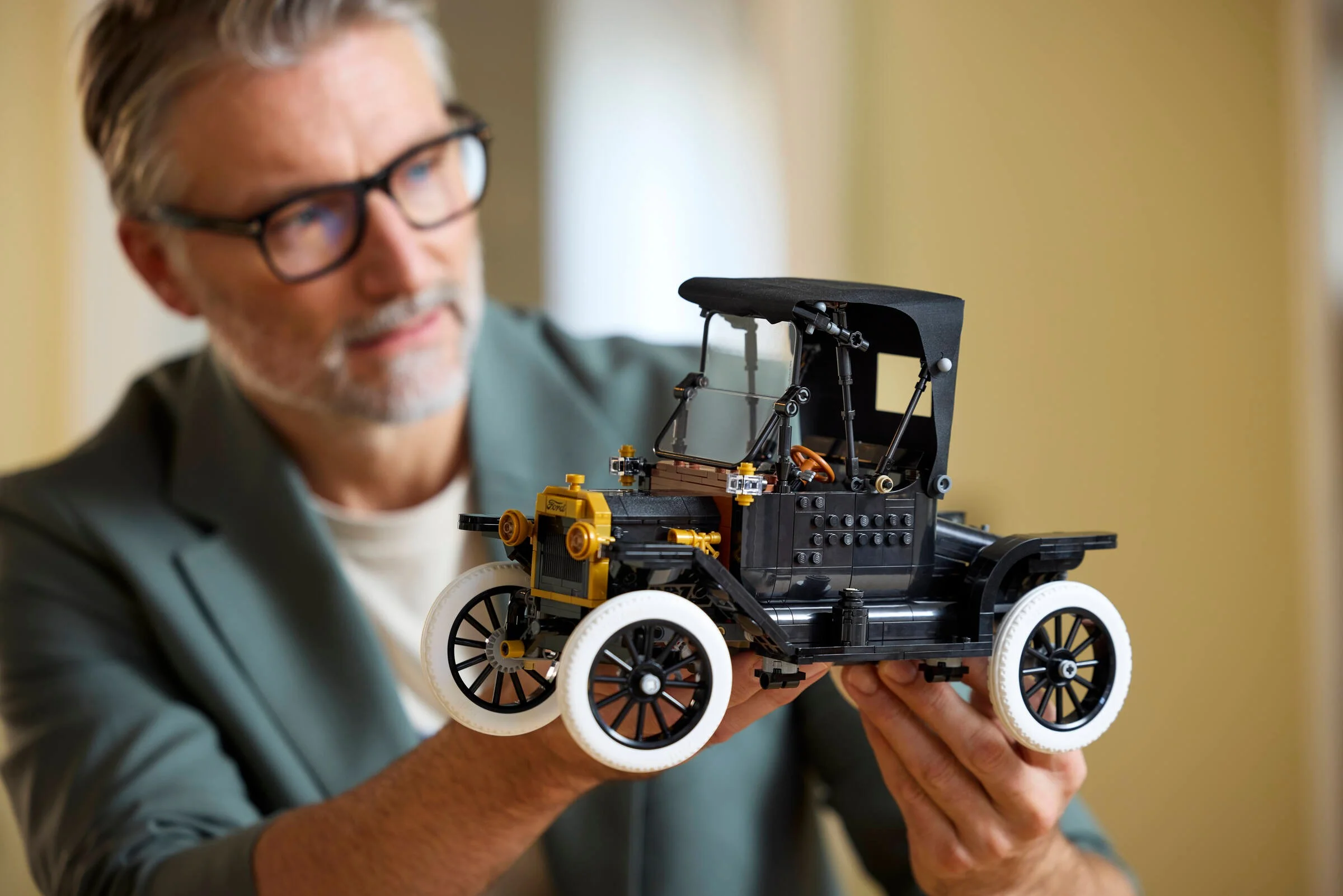 Bărbat prezintă modelul LEGO Ford Model T, arătând detaliile mașinii clasice.