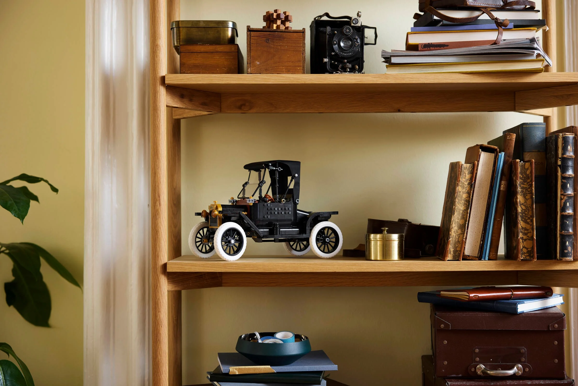 Modelul Ford Model T pe un raft de lemn, alături de alte obiecte decorative.