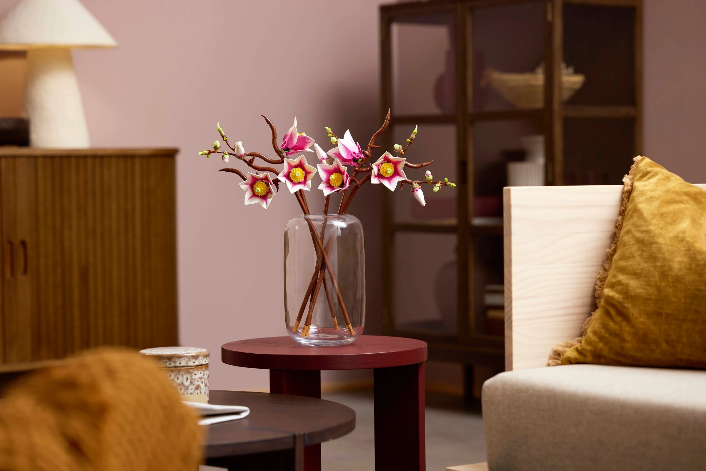 Ramuri de magnolie LEGO într-o vază, aranjate ca decor într-o cameră modernă, stilată.