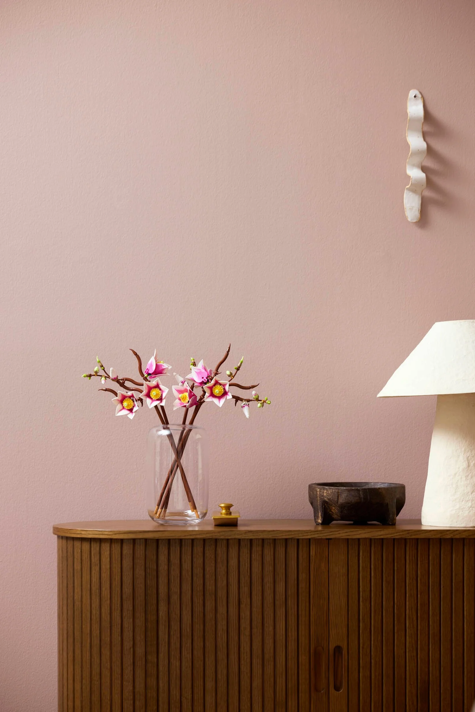 Ramuri de magnolie LEGO, într-o vază pe un dulap. Aspect elegant și modern.