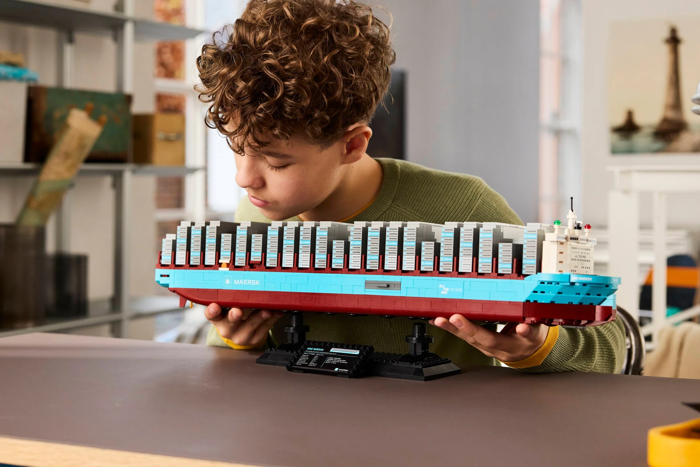 Un băiat admiră nava Maersk Dual-Fuel Container Vessel, un model LEGO detaliat.