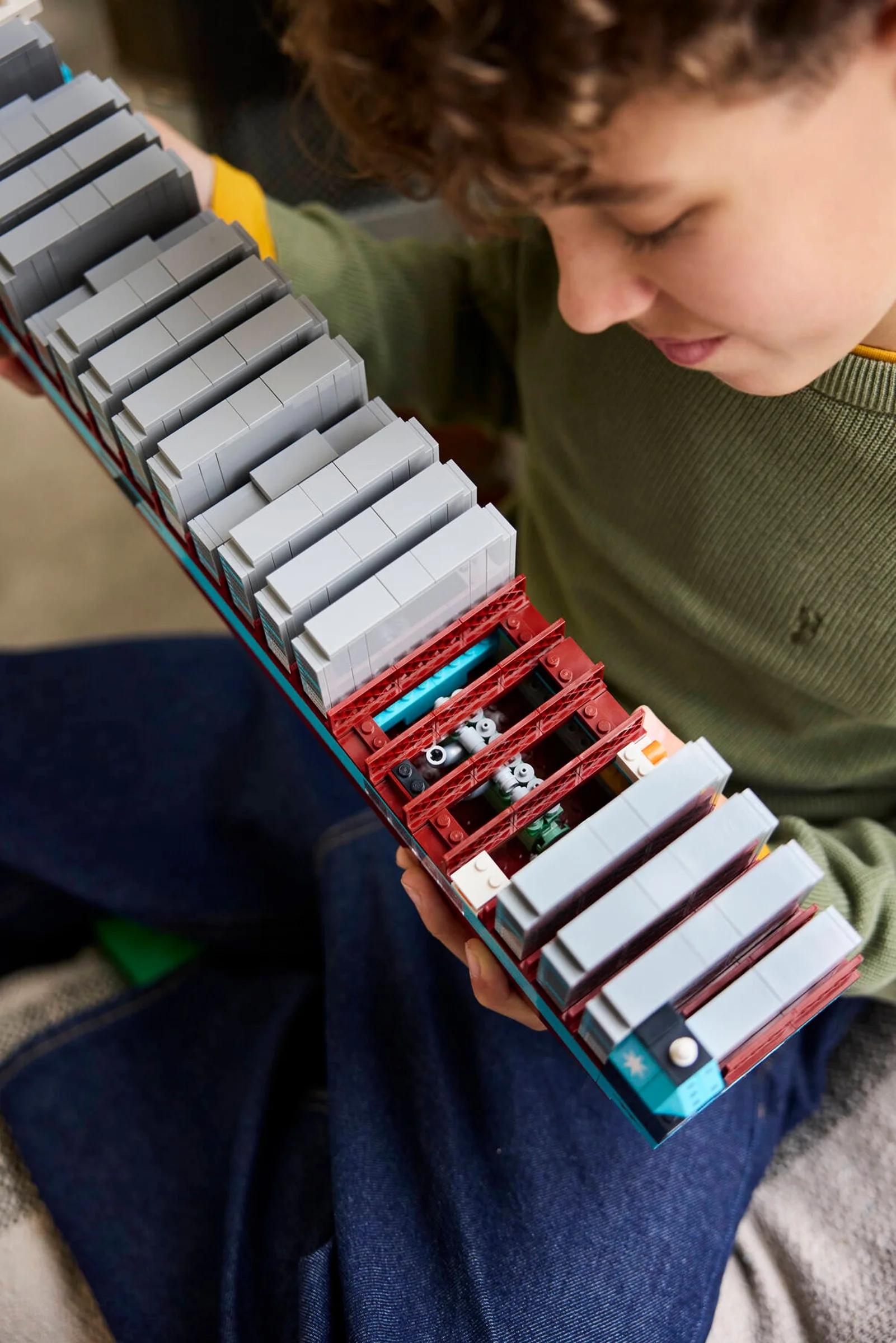 Băiat ține în mână modelul LEGO al navei Maersk, evidențiind detaliile construcției.