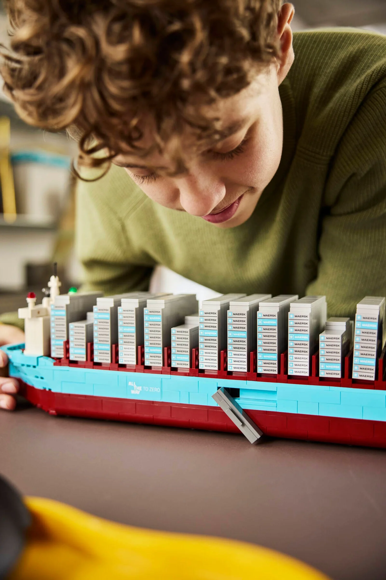 Copil construind vaporul LEGO Maersk, o experiență captivantă și detaliată.