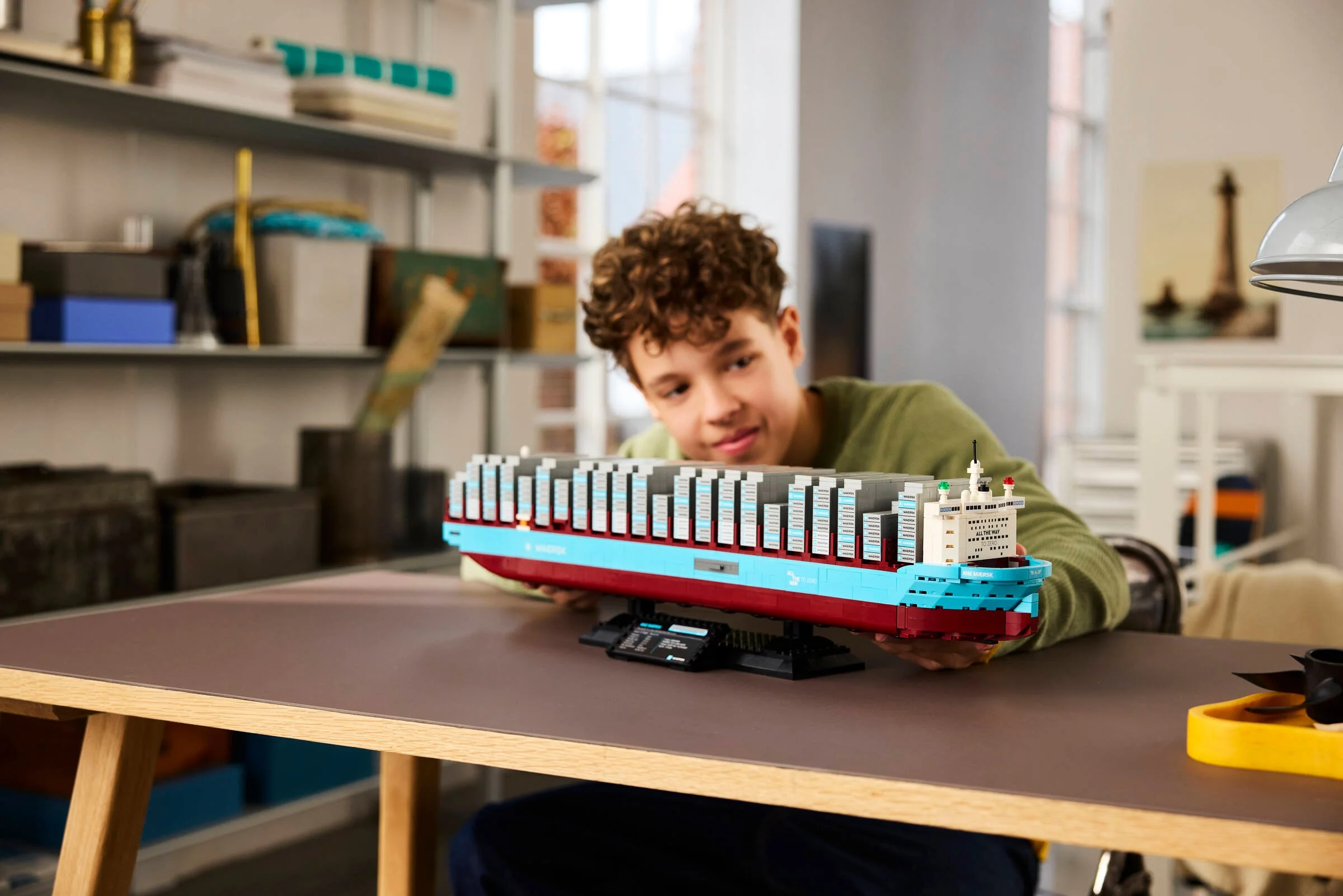 Un tânăr admiră nava Maersk, o construcție LEGO detaliată și impresionantă.