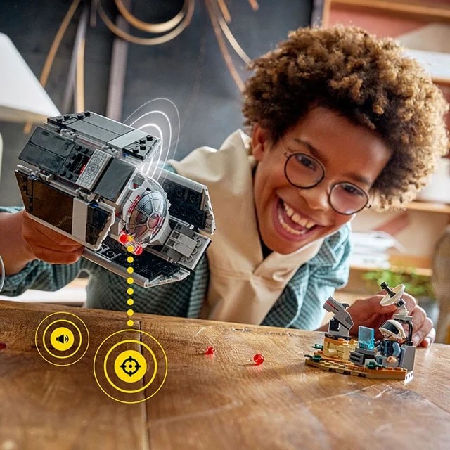 Copil se joacă cu TIE Fighter-ul lui Darth Vader și baza de comandă LEGO Star Wars.
