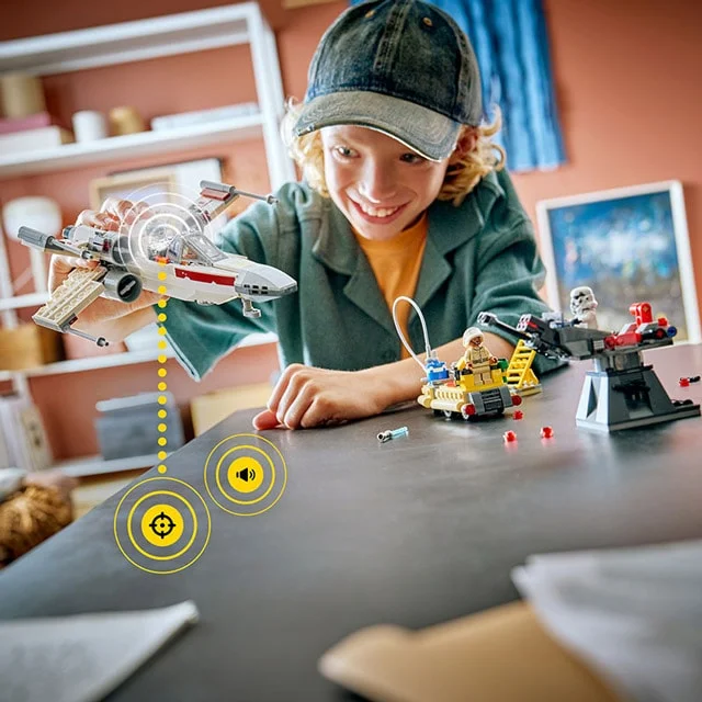 Copil zâmbitor se joacă cu setul LEGO Luke's Red Five X-wing, prezentând interacțiunea.