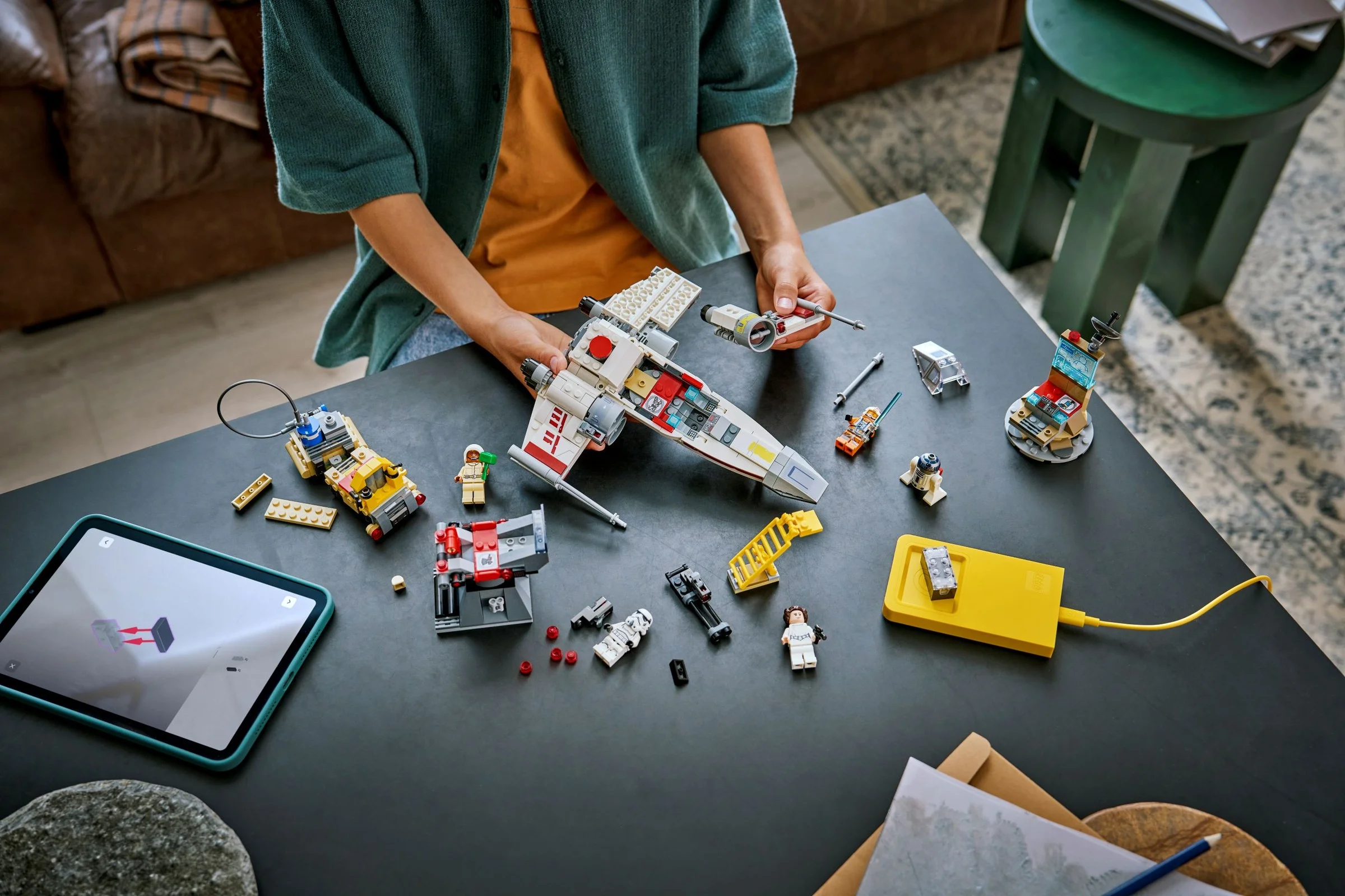 Imagine cu X-wing-ul lui Luke Skywalker (75423) și minifigurinele pe masă, asamblat parțial.