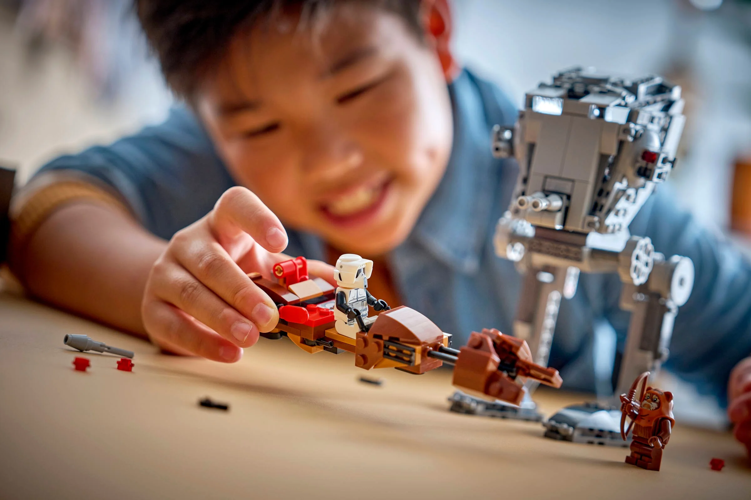 Copil se joacă cu setul LEGO 75424, atacând AT-ST cu o motocicletă de viteză.
