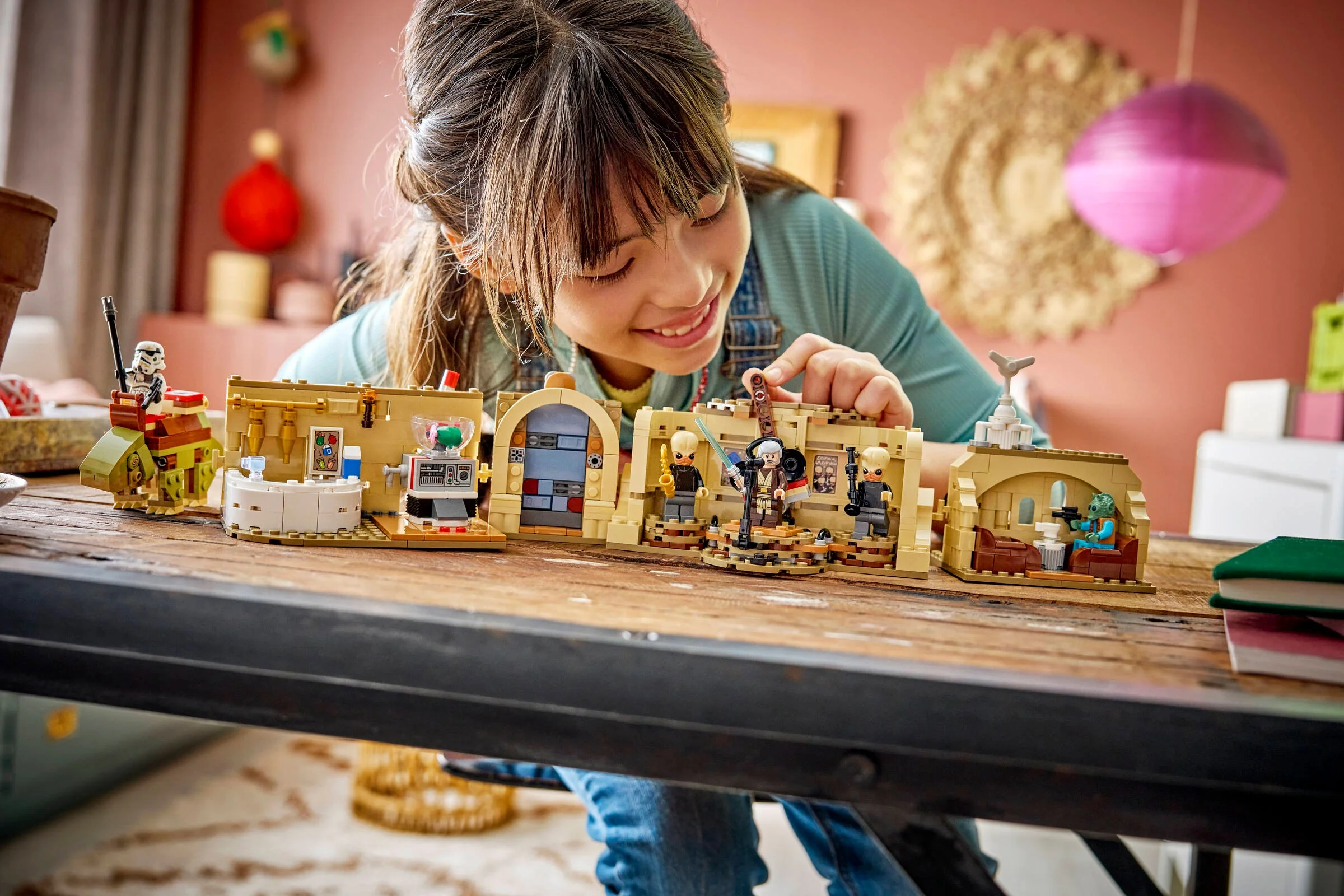 Fetiță interacționând cu setul LEGO Mos Eisley Cantina, zâmbind și explorând detaliile modelului.
