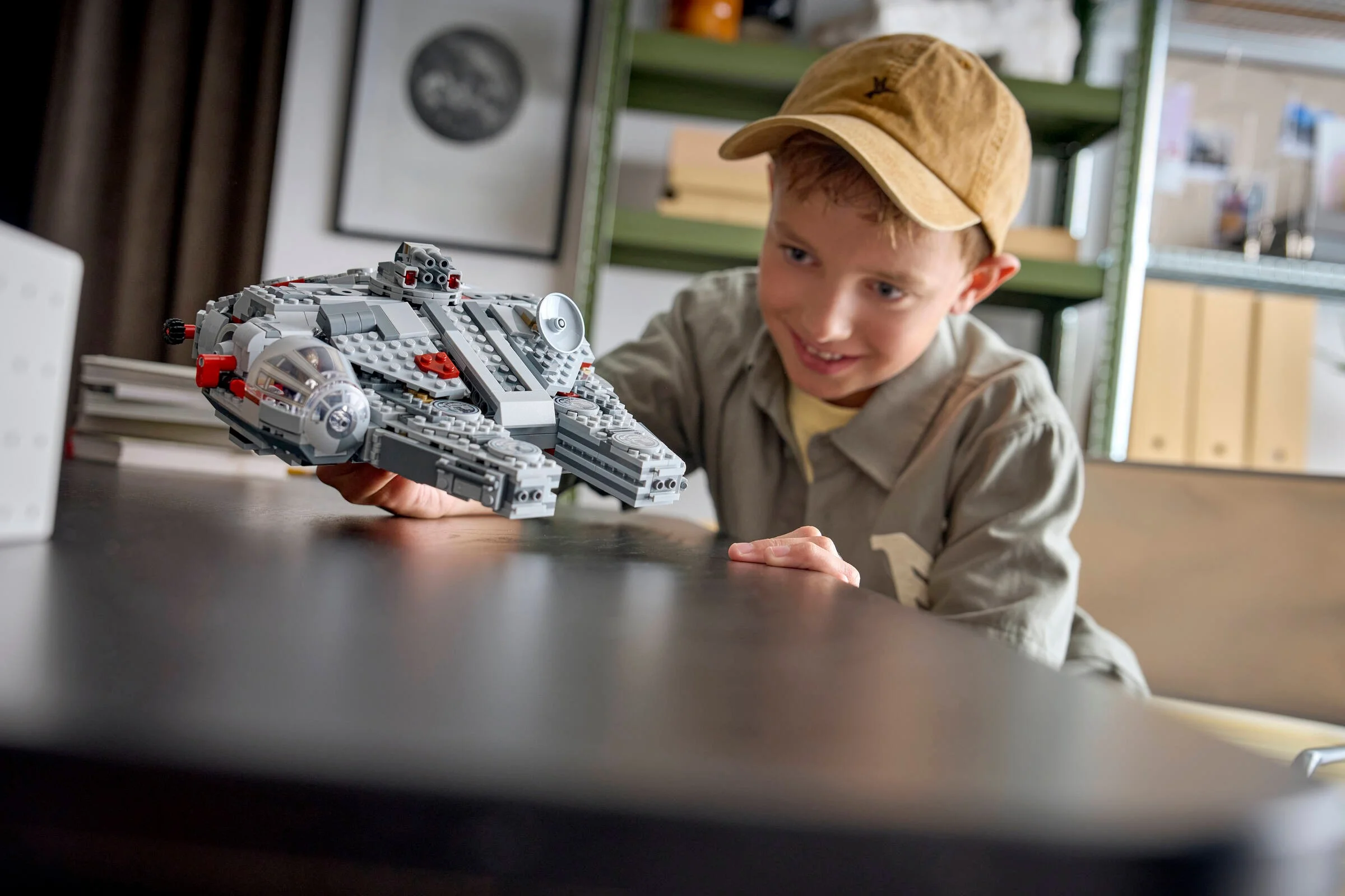 Un băiat admiră modelul Millennium Falcon construit, arătând detaliile navei.