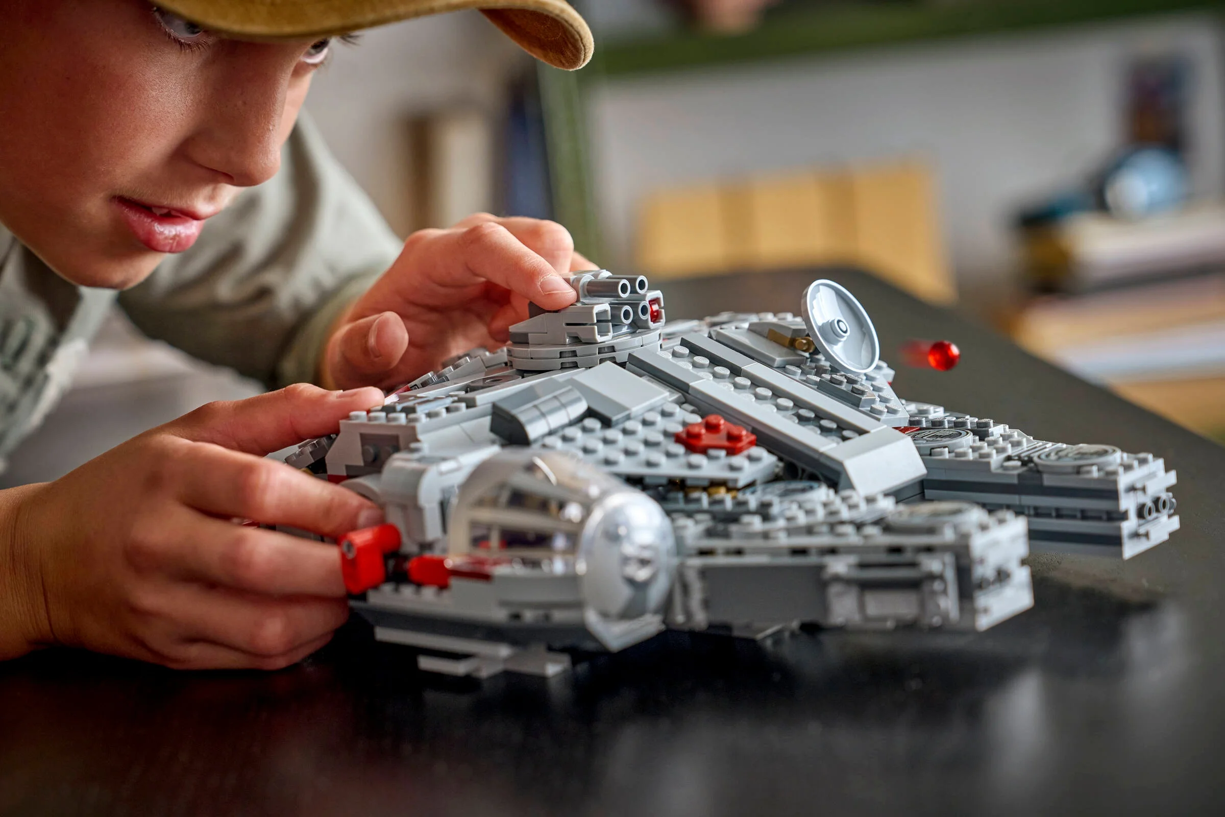 Copil construind modelul Millennium Falcon LEGO. Concentrare și joacă creativă.