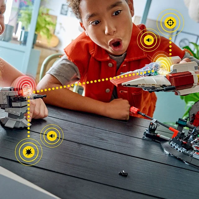 Copii se joacă cu A-wing și tureta din setul LEGO Star Wars 75427, simulând o luptă.