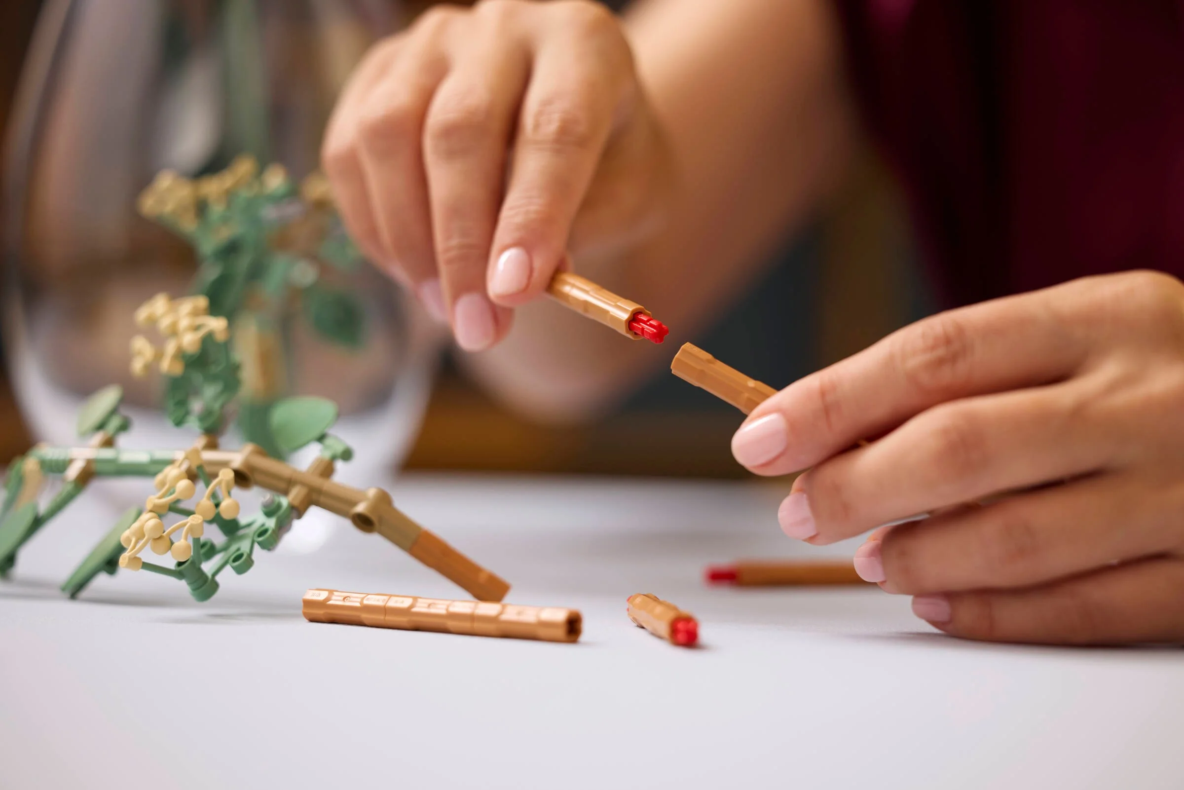 Construirea buchetului LEGO cu tulpini maro și detalii florale verzi și galbene.