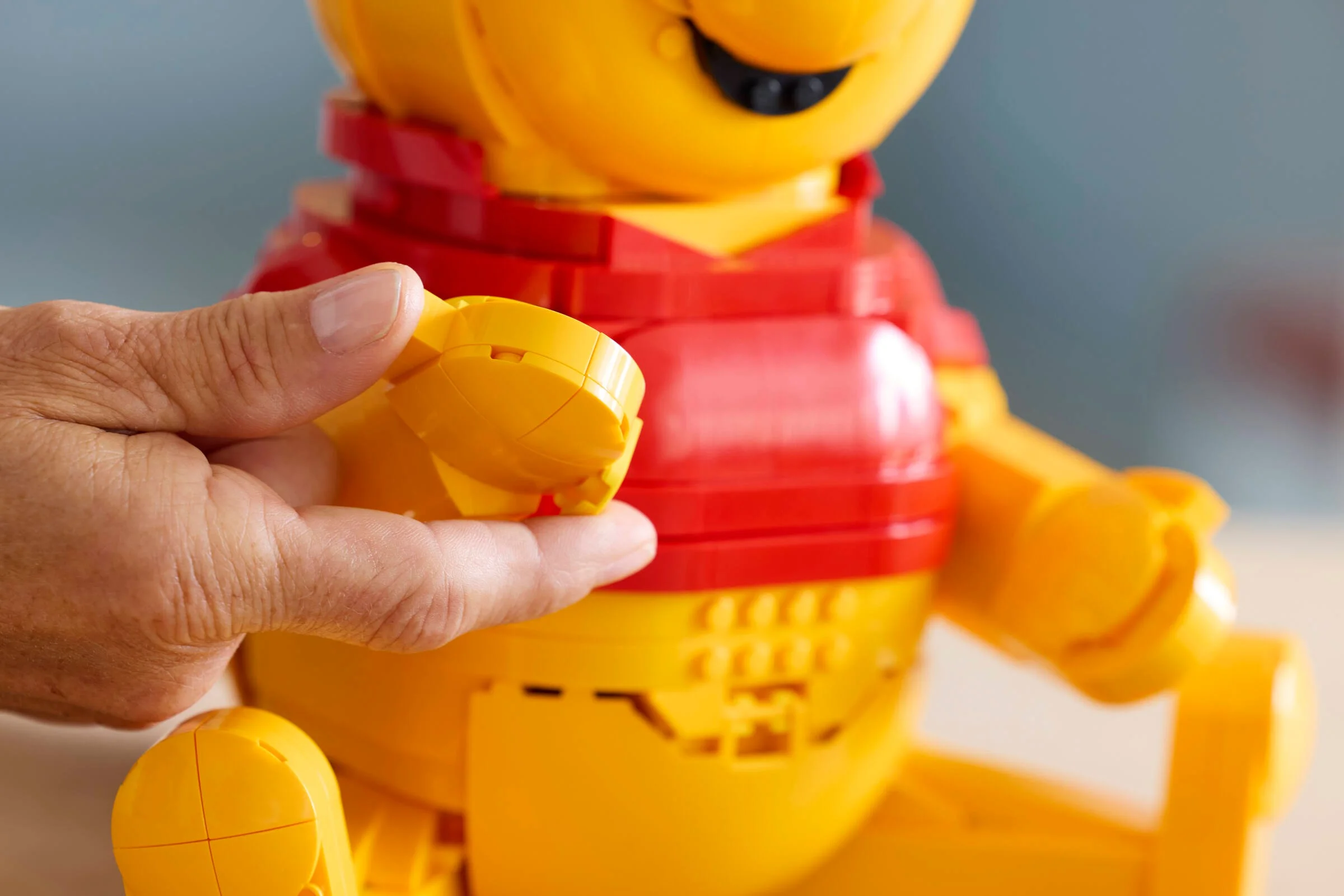 Construirea lui Winnie the Pooh din LEGO. Detaliu cu mâna montând o piesă. 