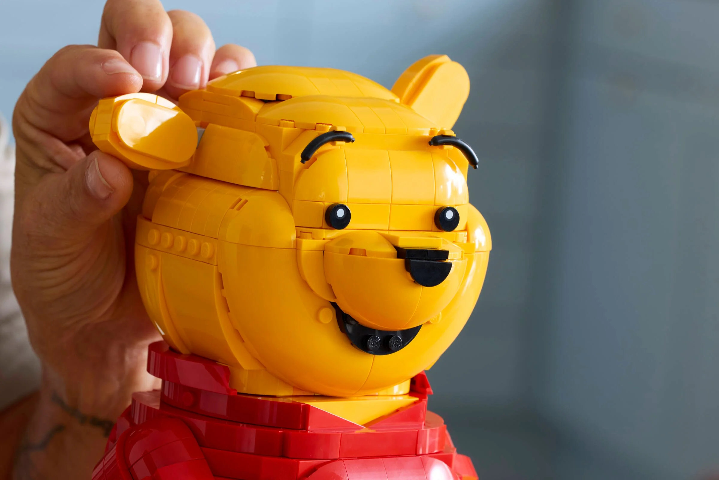 Prim-plan cu Winnie the Pooh LEGO, ureche detașată, detalii construcție vizibile.