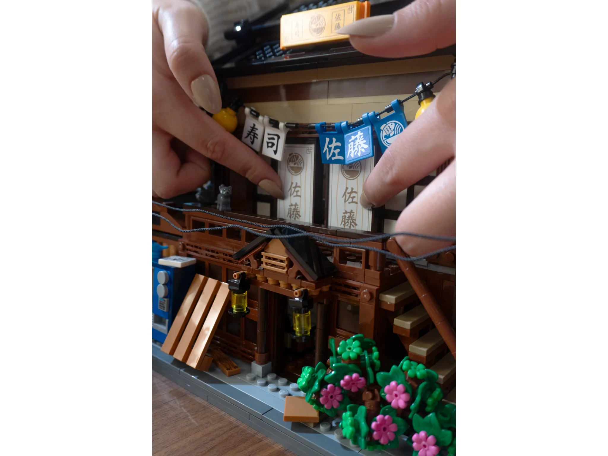Prim-plan restaurant LEGO sushi. Detalii cu inscripții japoneze și decor floral. Experiență tactilă.