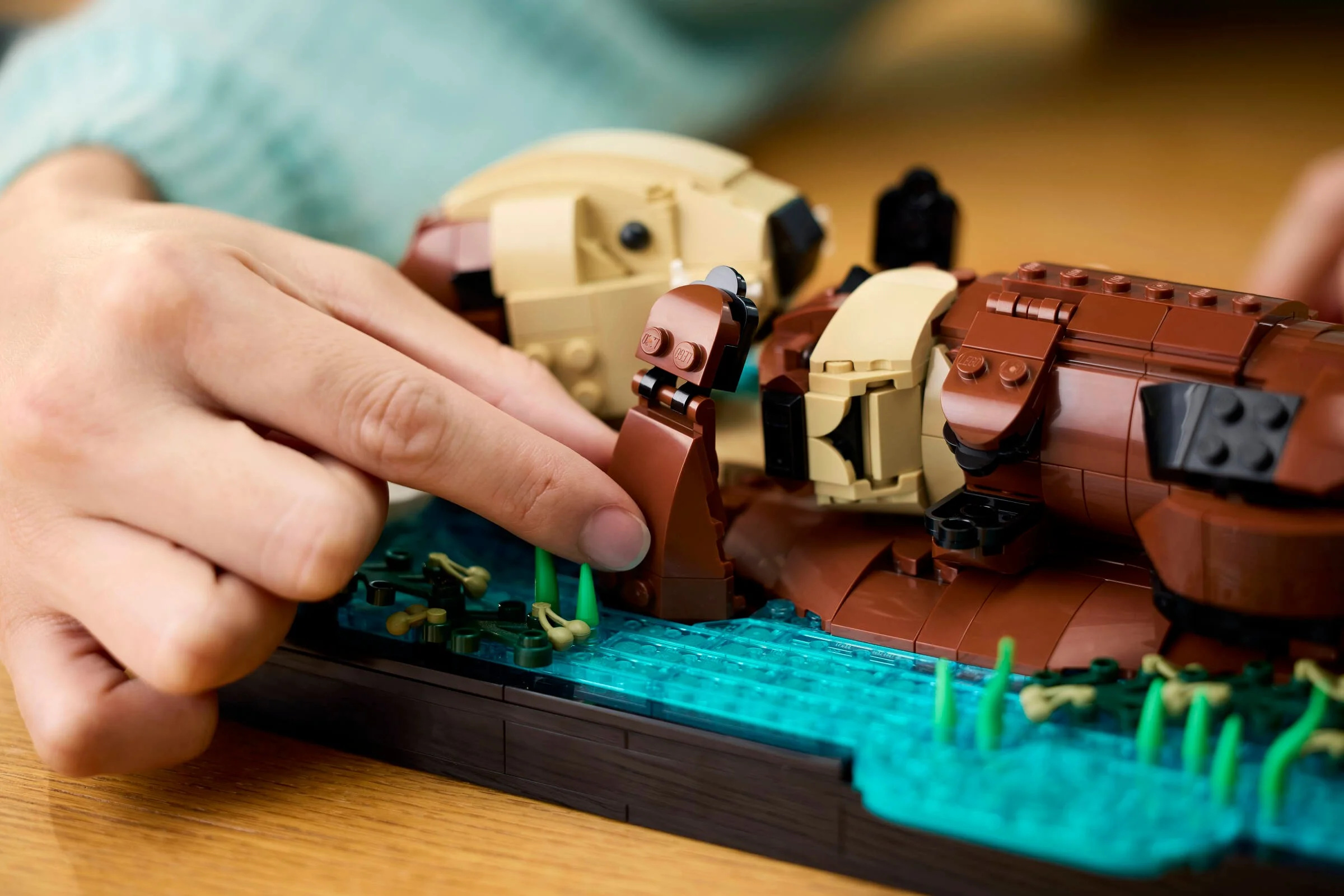 Construirea vidrelor LEGO. O persoană adaugă un element la modelul plutitor.