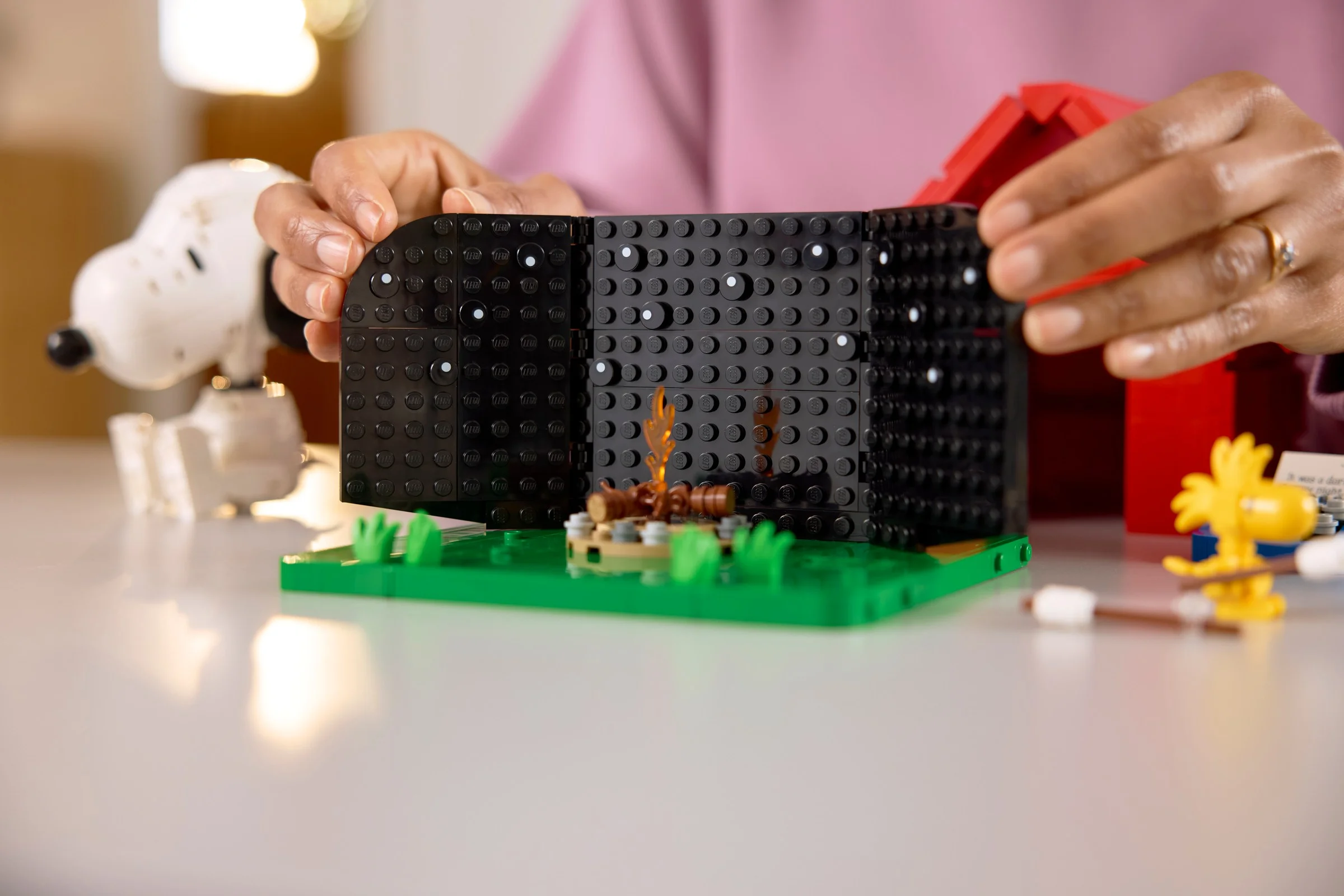 Construirea căsuței lui Snoopy din LEGO. Se văd pereții interiori și focul de tabără.