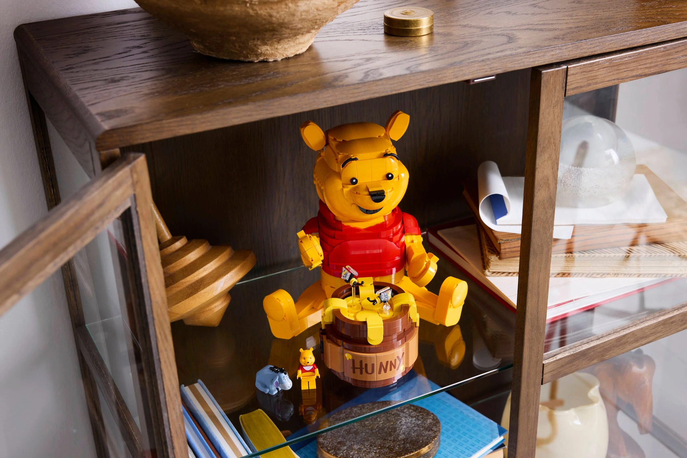 Winnie the Pooh LEGO în vitrină, cu un borcan de miere și mini-figurine Eeyore și Pooh.