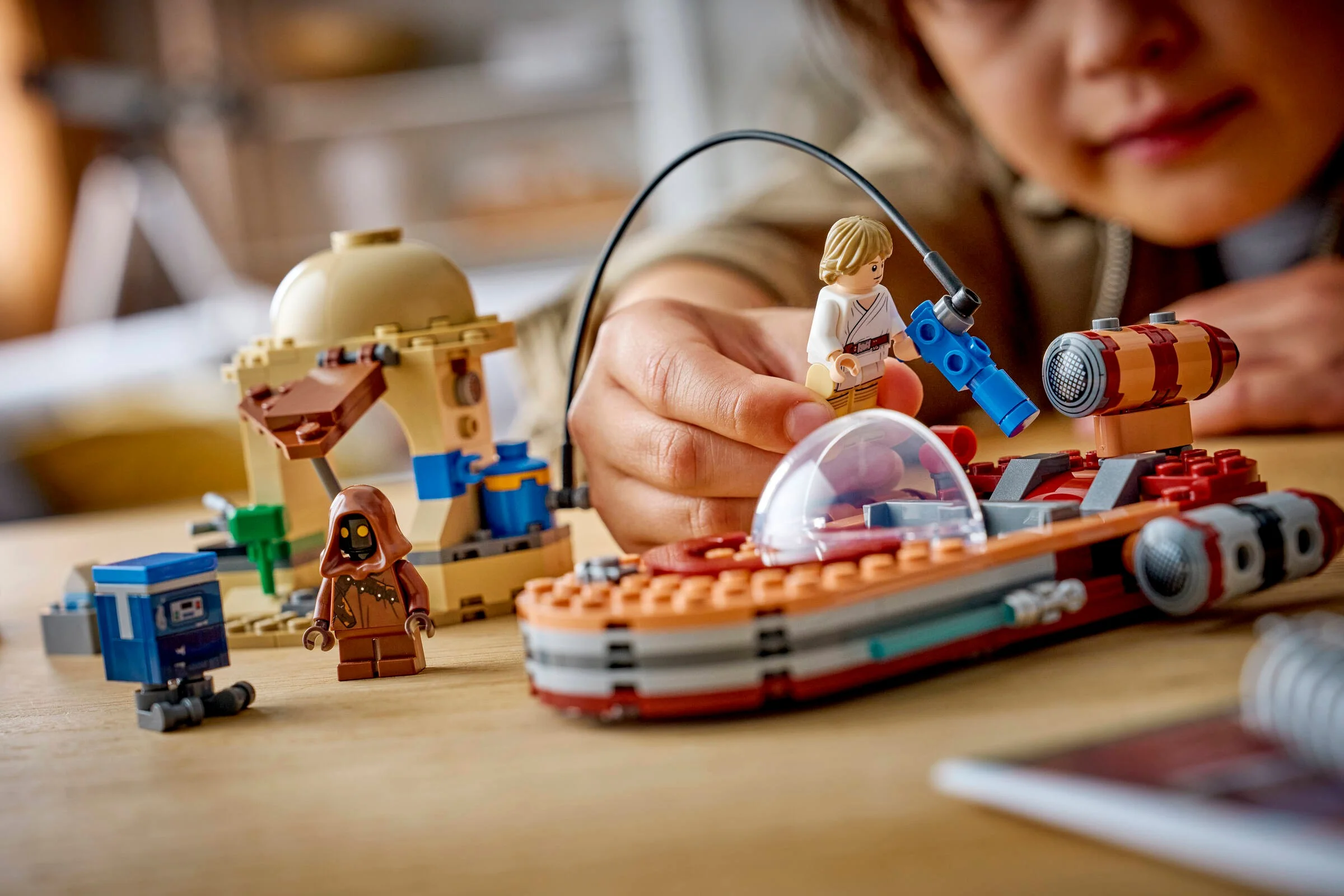 Copil se joacă cu setul LEGO Landspeeder. Imagine detaliată cu minifigurinele și modelul.