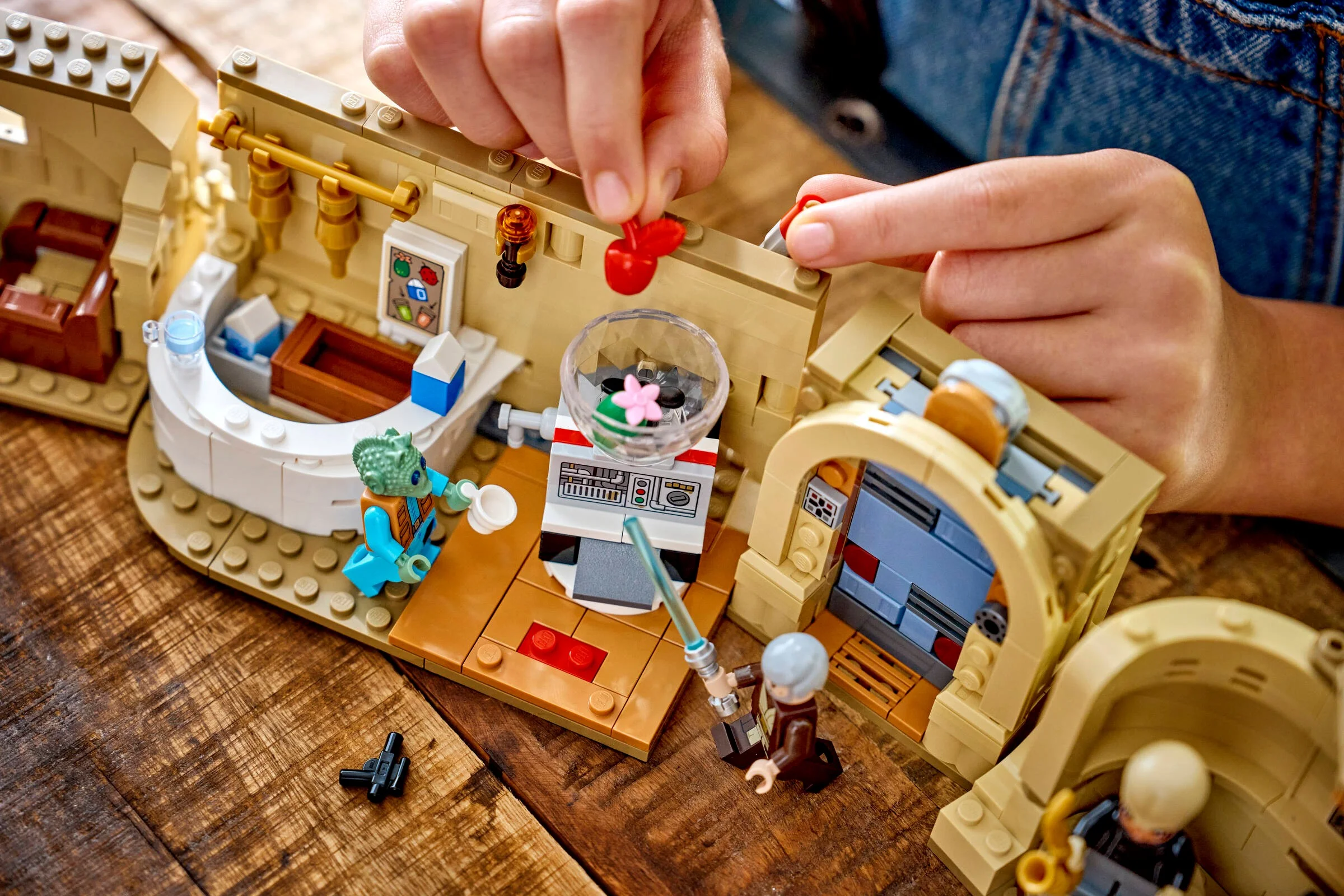 Detalii despre Cantina Mos Eisley LEGO, o persoană atașând o piesă. Elemente iconice.