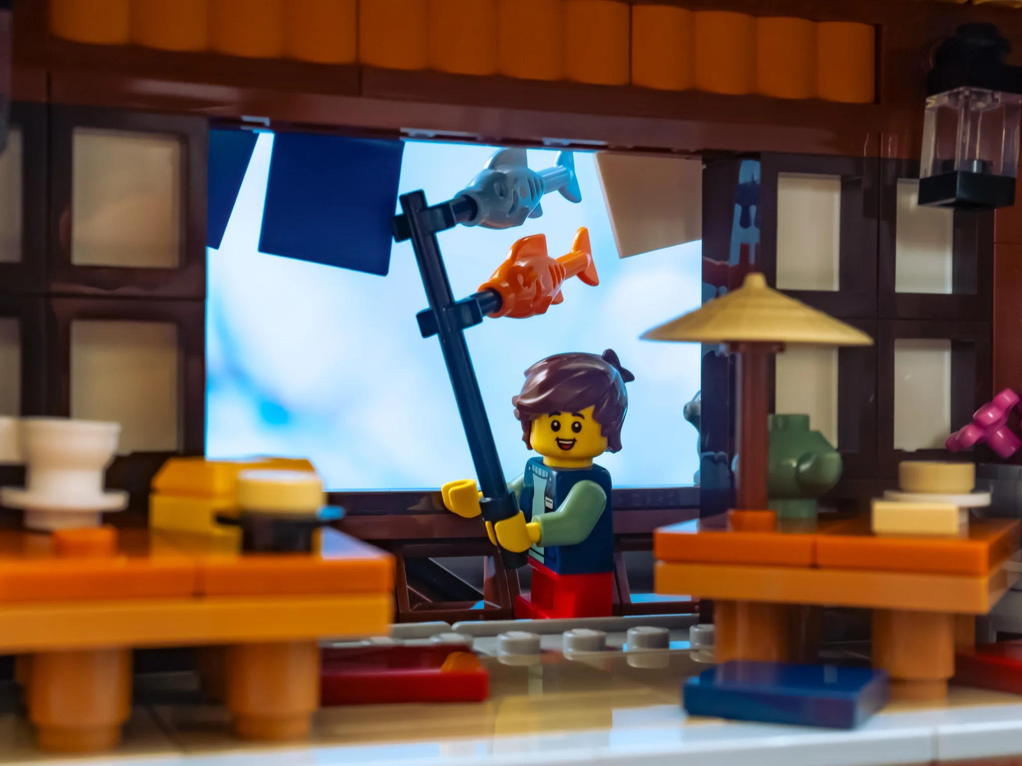 Minifigurina pescuind în restaurantul LEGO. O scenă detaliată cu pești agățați.