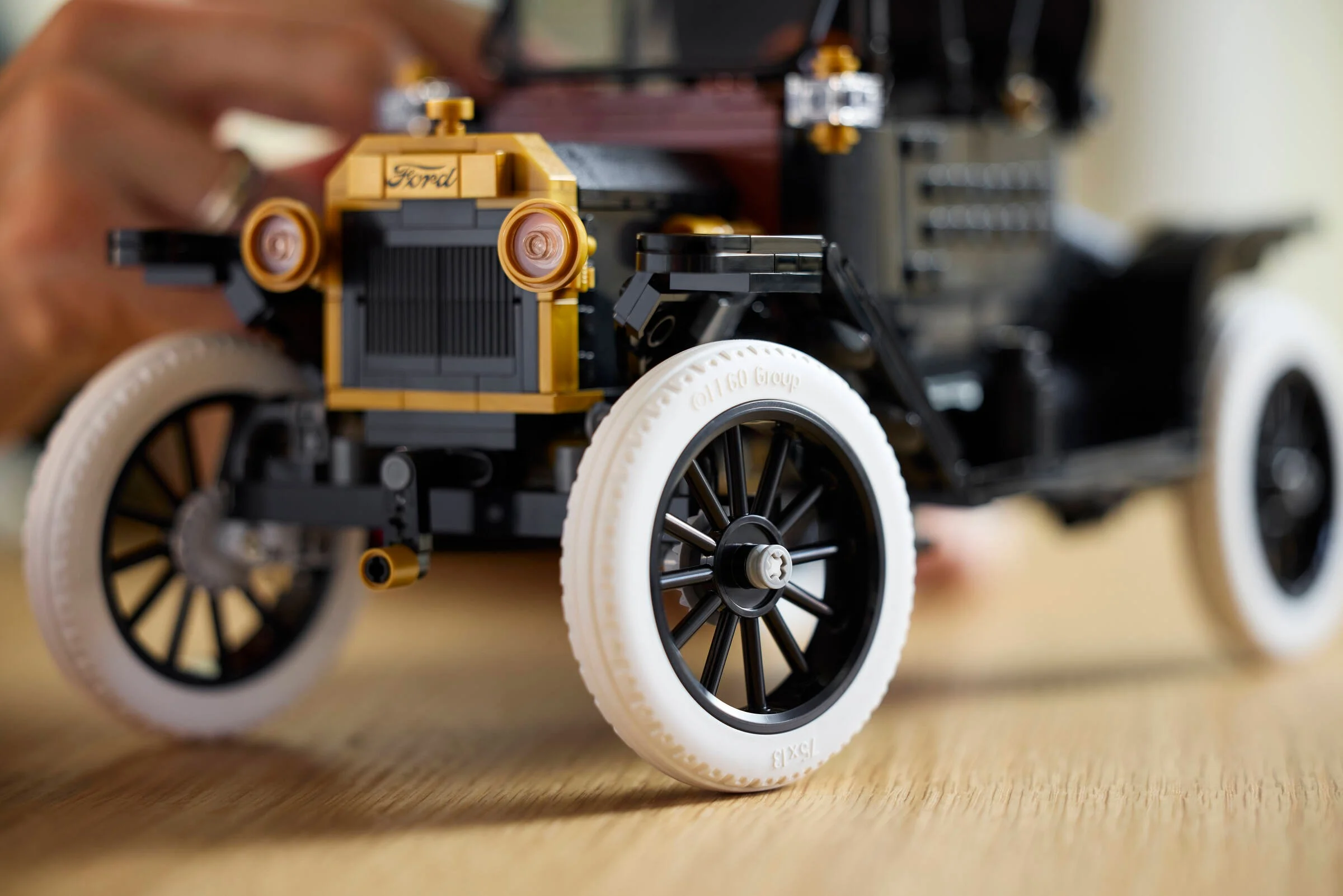 Prim-plan detaliat al modelului Ford Model T din LEGO, cu accent pe grila frontală și roți.