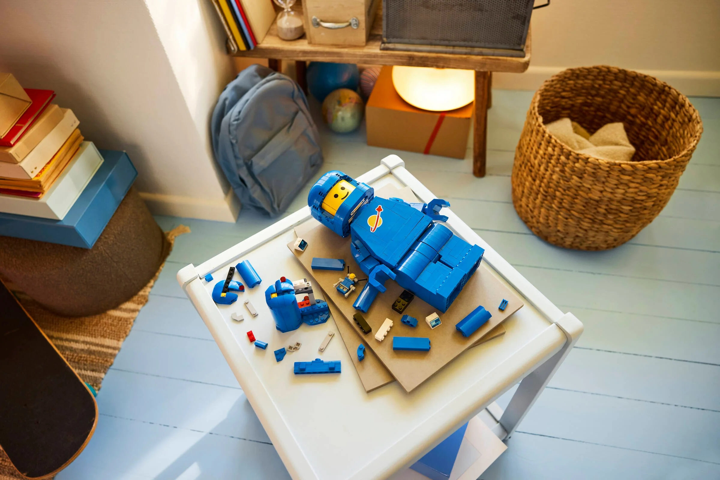Setul LEGO 40921 prezintă un astronaut albastru supradimensionat, în construcție. Piesele sunt împrăștiate pe masă.