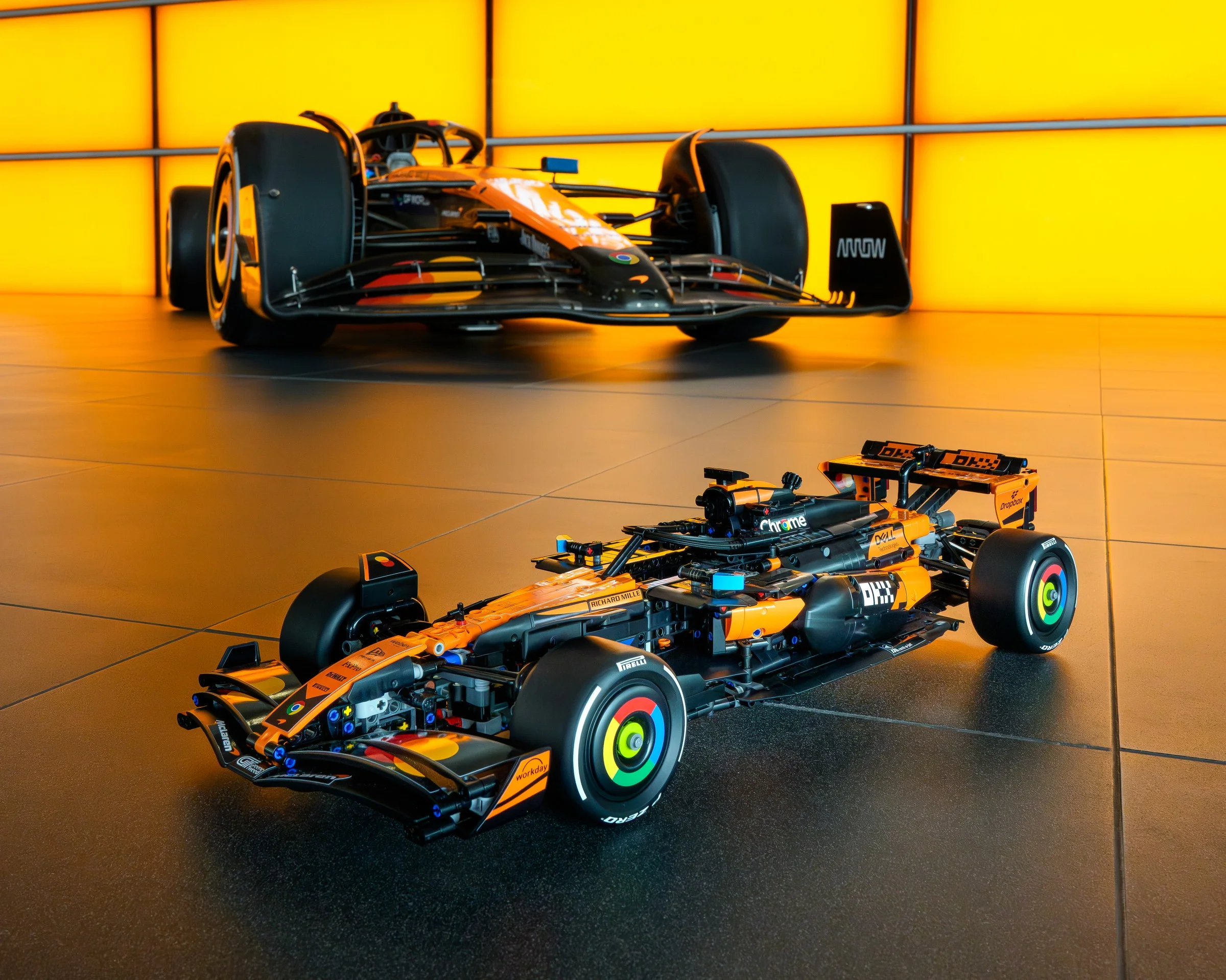 Două modele McLaren F1 MCL39, cu detalii fine și culori vii, portocaliu și negru.