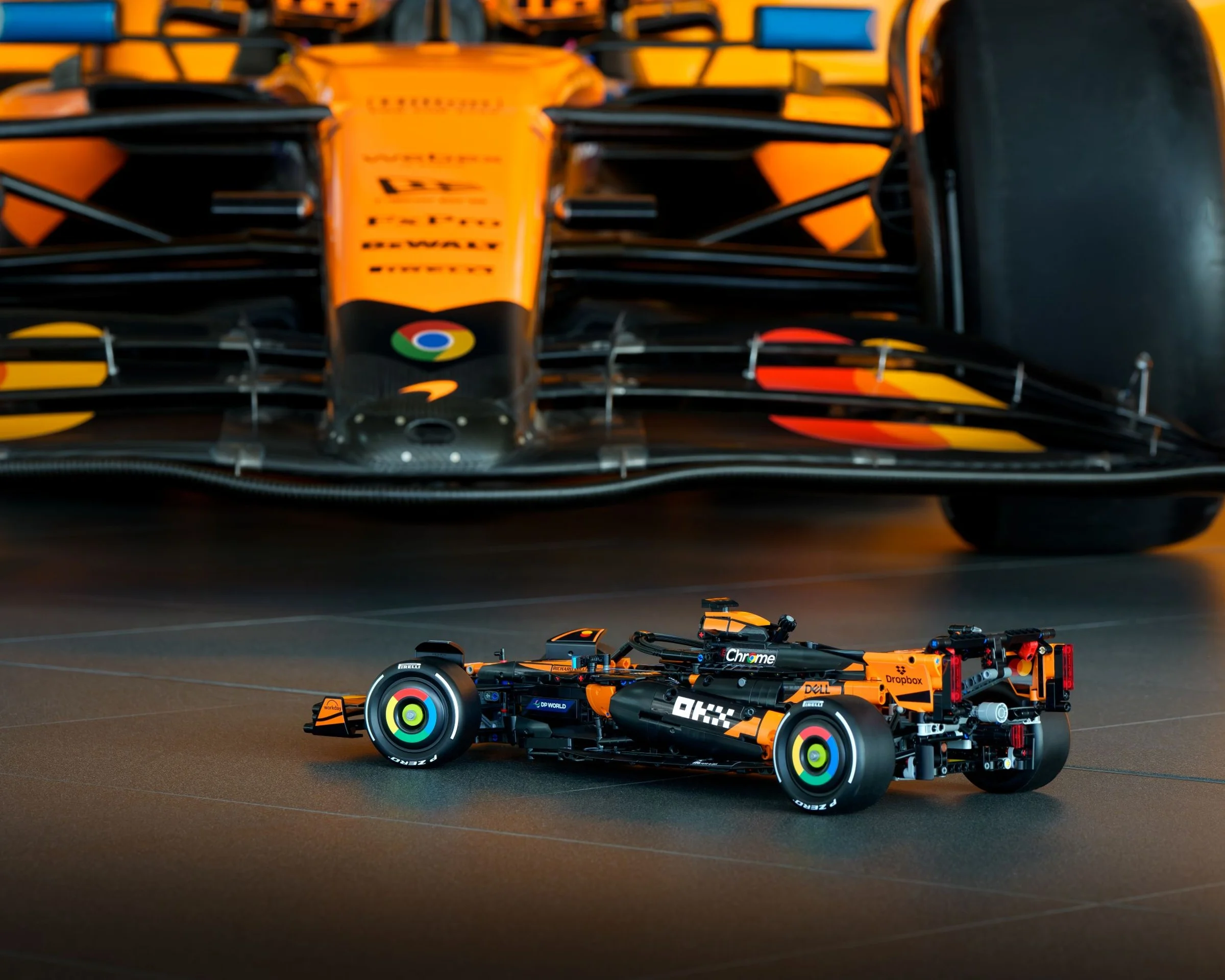 Modelul LEGO Technic McLaren F1 MCL39, o replică detaliată, alături de mașina de curse reală, în fundal.