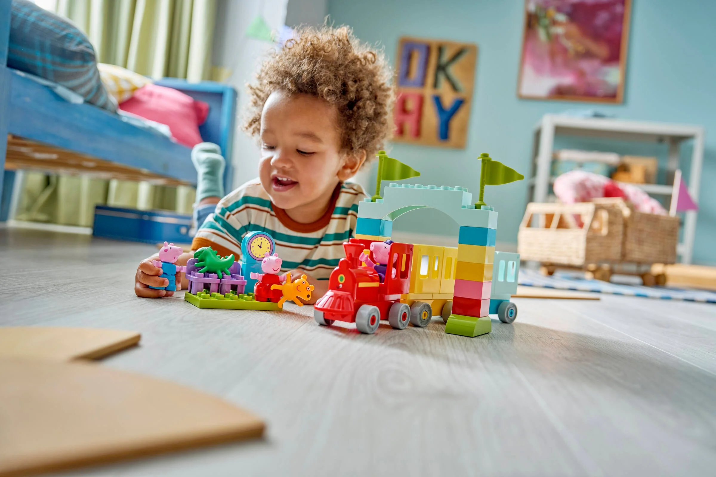 Copil se joacă cu setul LEGO Duplo Trenulețul cu Bunicul Purceluș. Setul include un tren colorat și figurine.